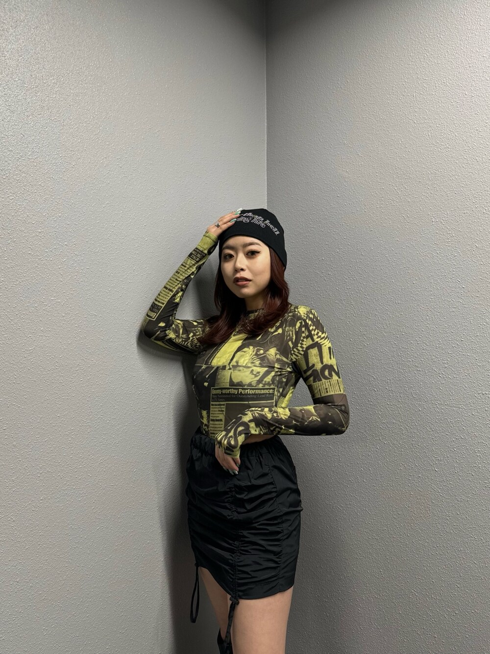 イエロー系のTシャツ/カットソー、ブラック系のスカート、ブラック系のブーツを着用したレディースの冬コーディネートの2枚目の写真