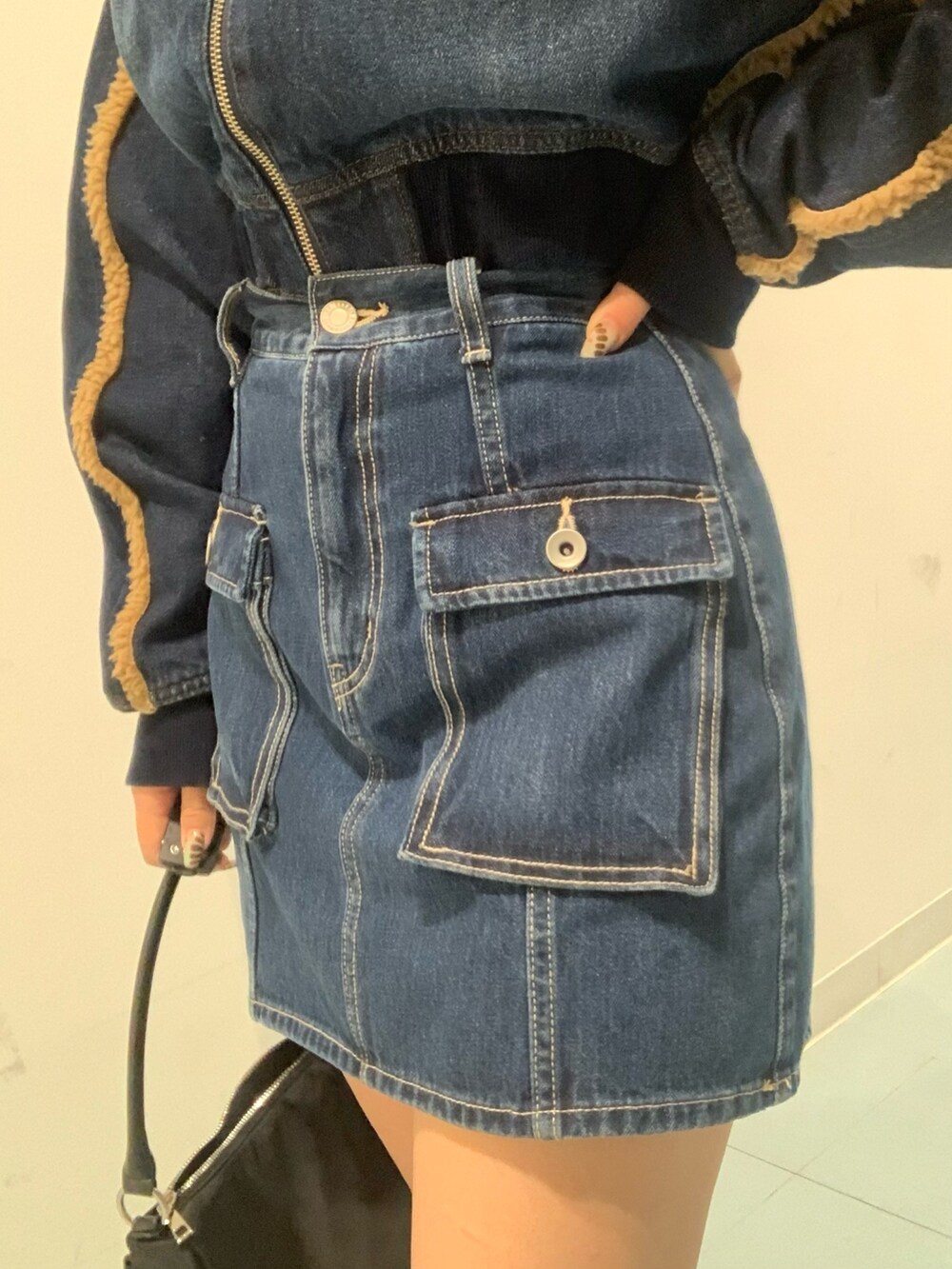 ブルー系のブルゾン、ブルー系のデニムスカート、ブラック系のブーツを着用したレディースの秋コーディネートの5枚目の写真