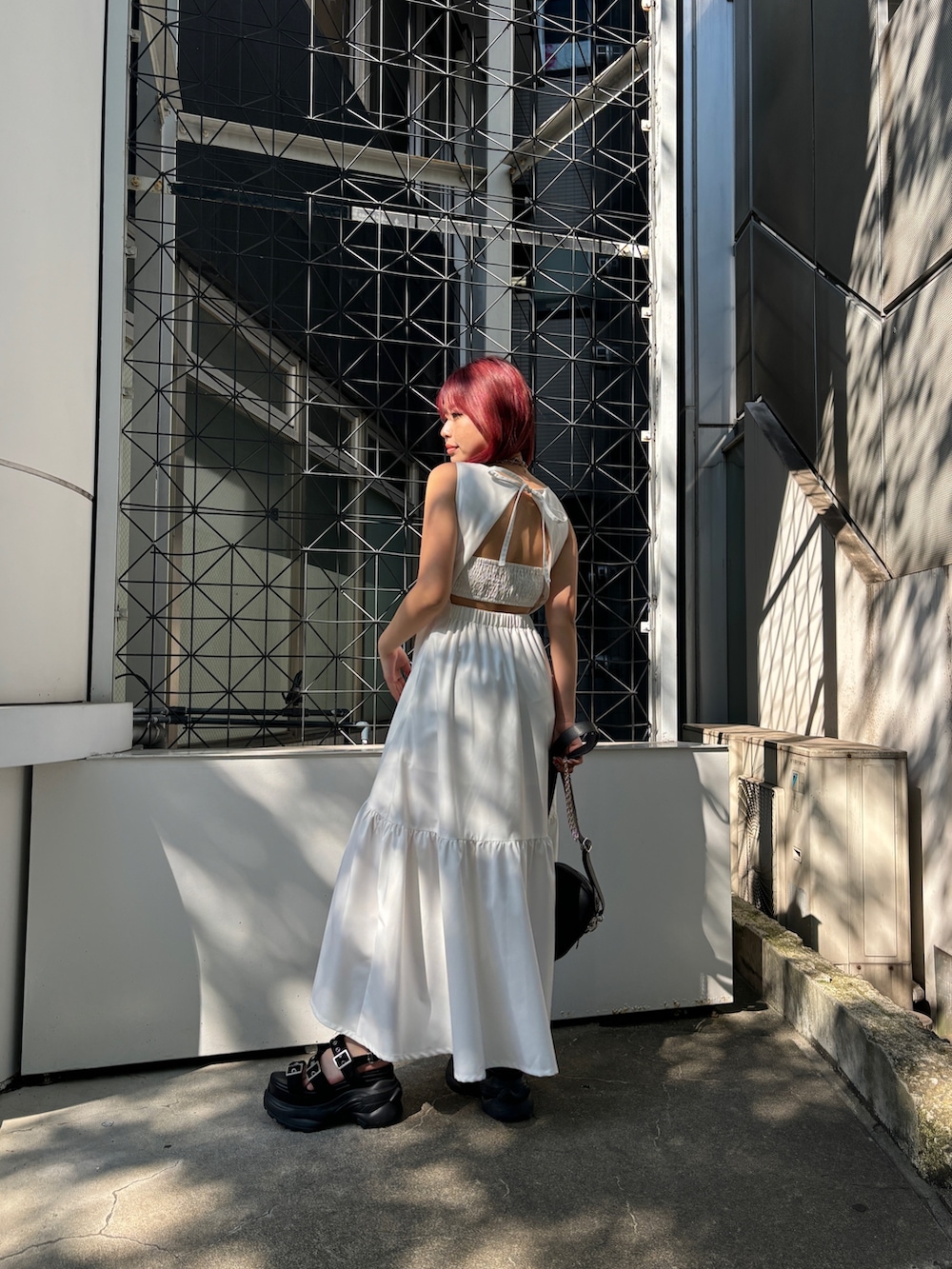 ホワイト系のワンピース、ブラック系のショルダーバッグ、ブラック系のサンダルを着用したレディースの夏コーディネートの3枚目の写真