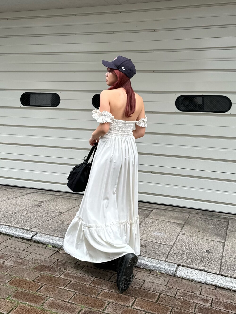 ホワイト系のワンピース、ブラック系のショルダーバッグ、ブラック系のブーツを着用したレディースの春コーディネートの2枚目の写真