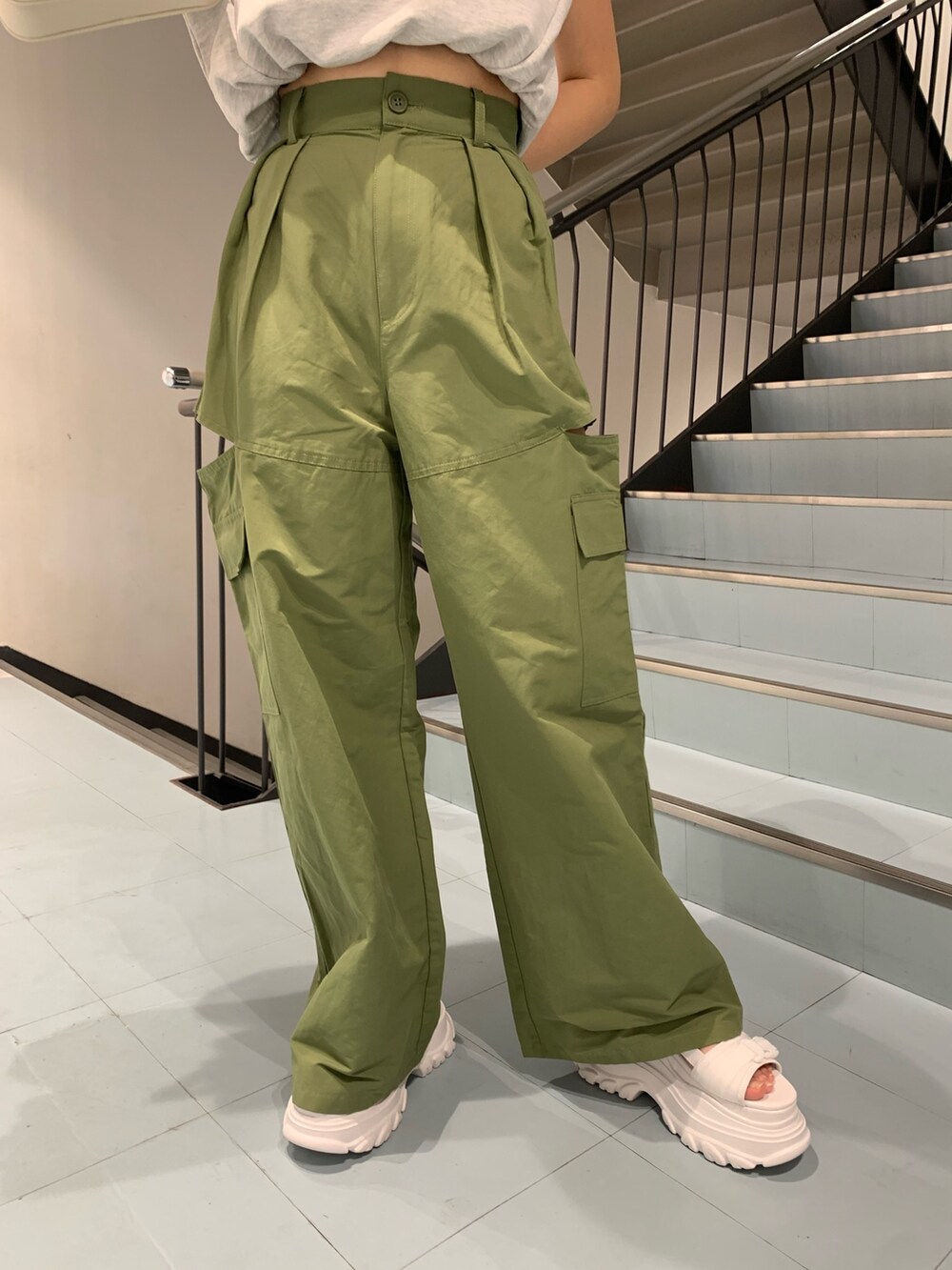 グレー系のタンクトップ、グリーン系のカーゴパンツ、ホワイト系のショルダーバッグを着用したレディースの春コーディネートの3枚目の写真