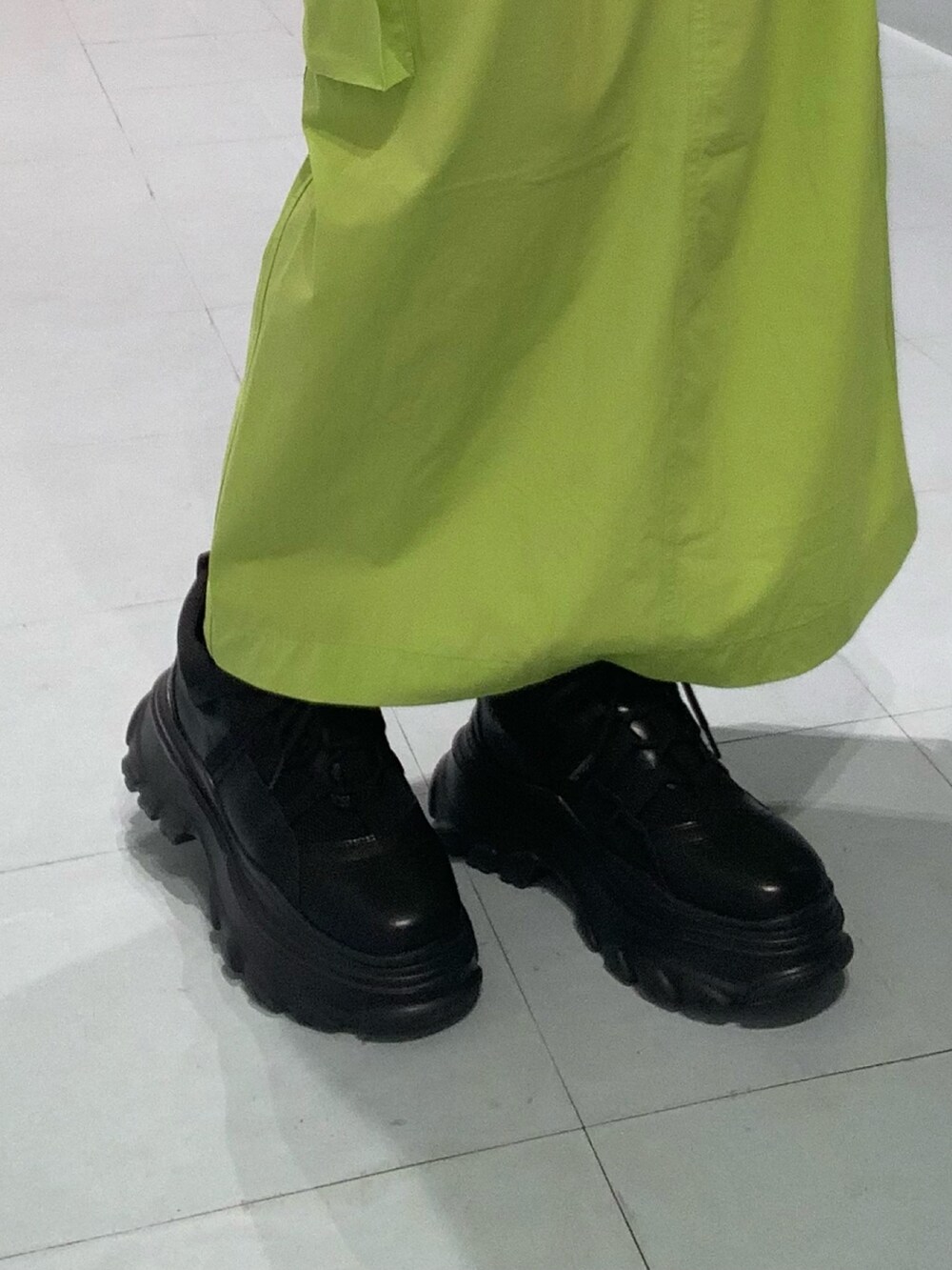 ブラック系のTシャツ/カットソー、グリーン系のスカート、ブラック系のスニーカーを着用したレディースの春コーディネートの7枚目の写真