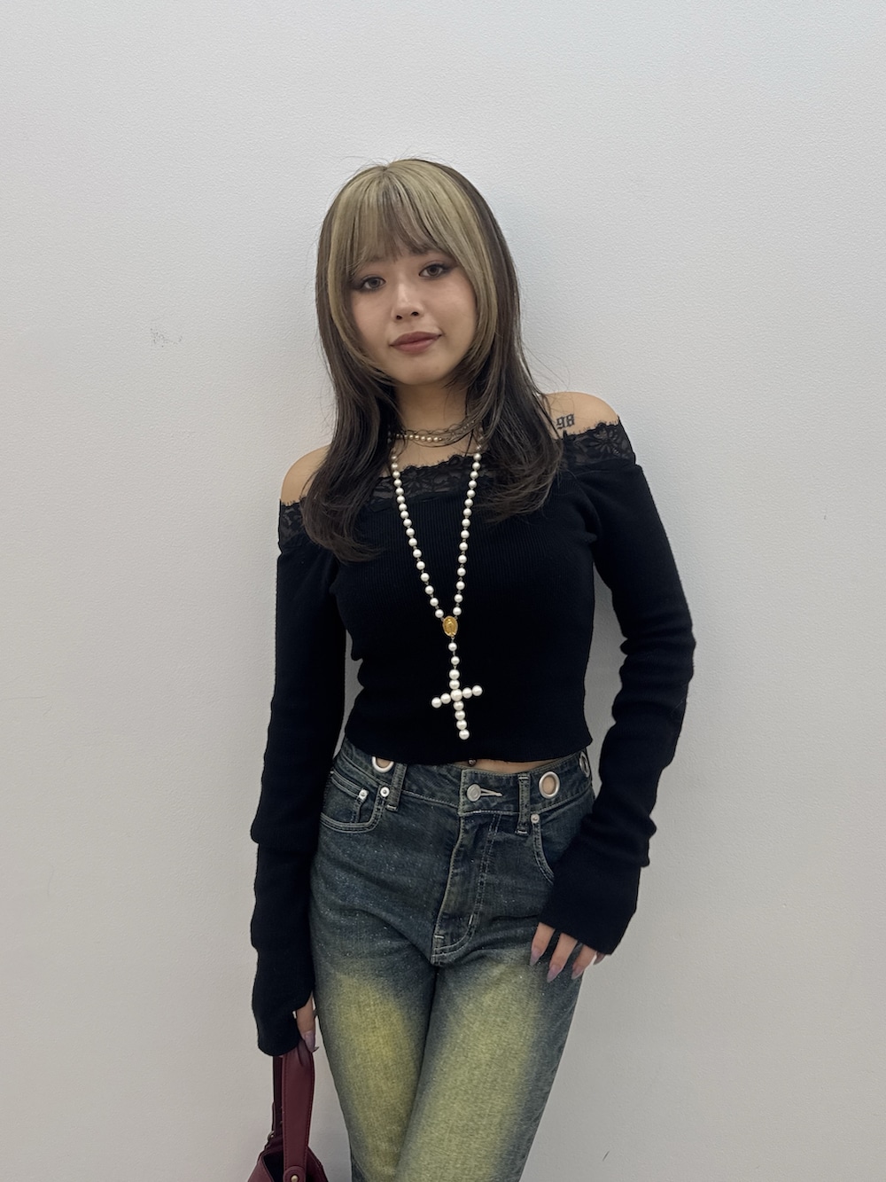 ブラック系のニット/セーター、ブルー系のデニムパンツ、レッド系のハンドバッグを着用したレディースの秋コーディネートの4枚目の写真