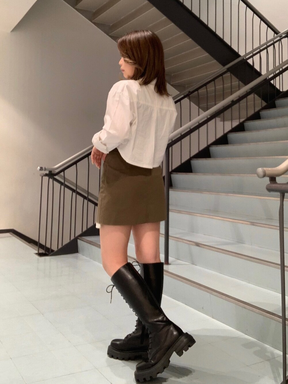 ブラック系のTシャツ/カットソー、ホワイト系のシャツ/ブラウス、グリーン系のスカートを着用したレディースの春コーディネートの2枚目の写真