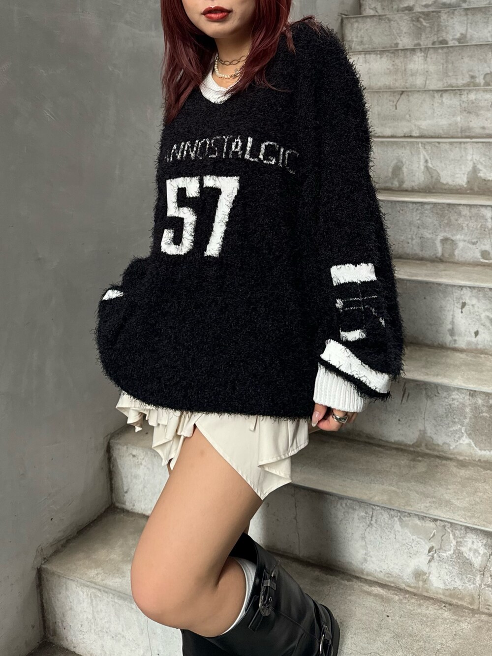 ブラック系のニット/セーター、ホワイト系のスカート、ブラック系のブーツを着用したレディースの秋コーディネートの3枚目の写真