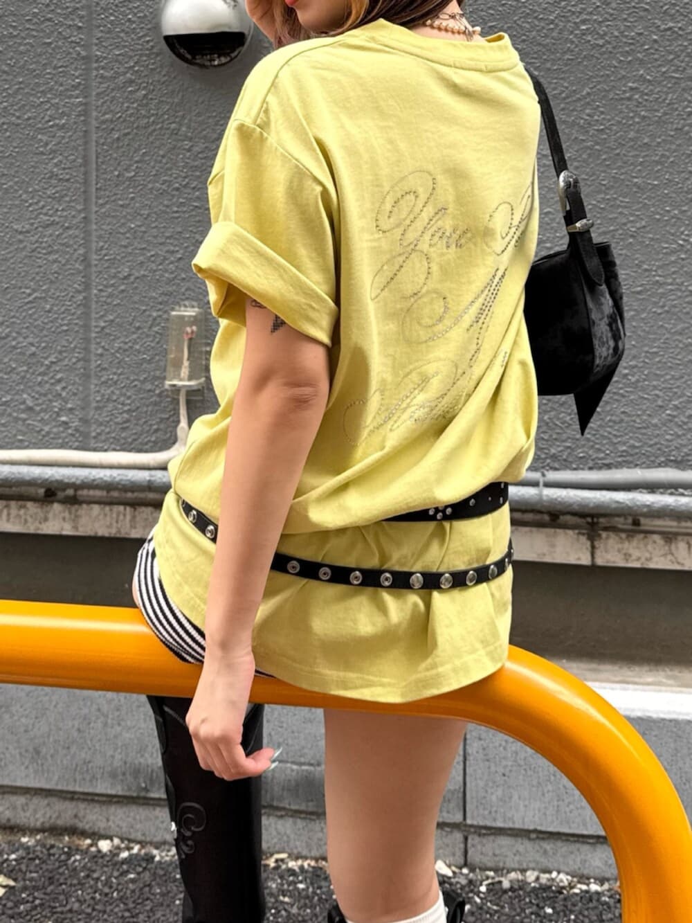 ブラック系のブーツ、ブラック系のハンドバッグ、イエロー系のTシャツ/カットソーを着用したレディースの夏コーディネートの5枚目の写真