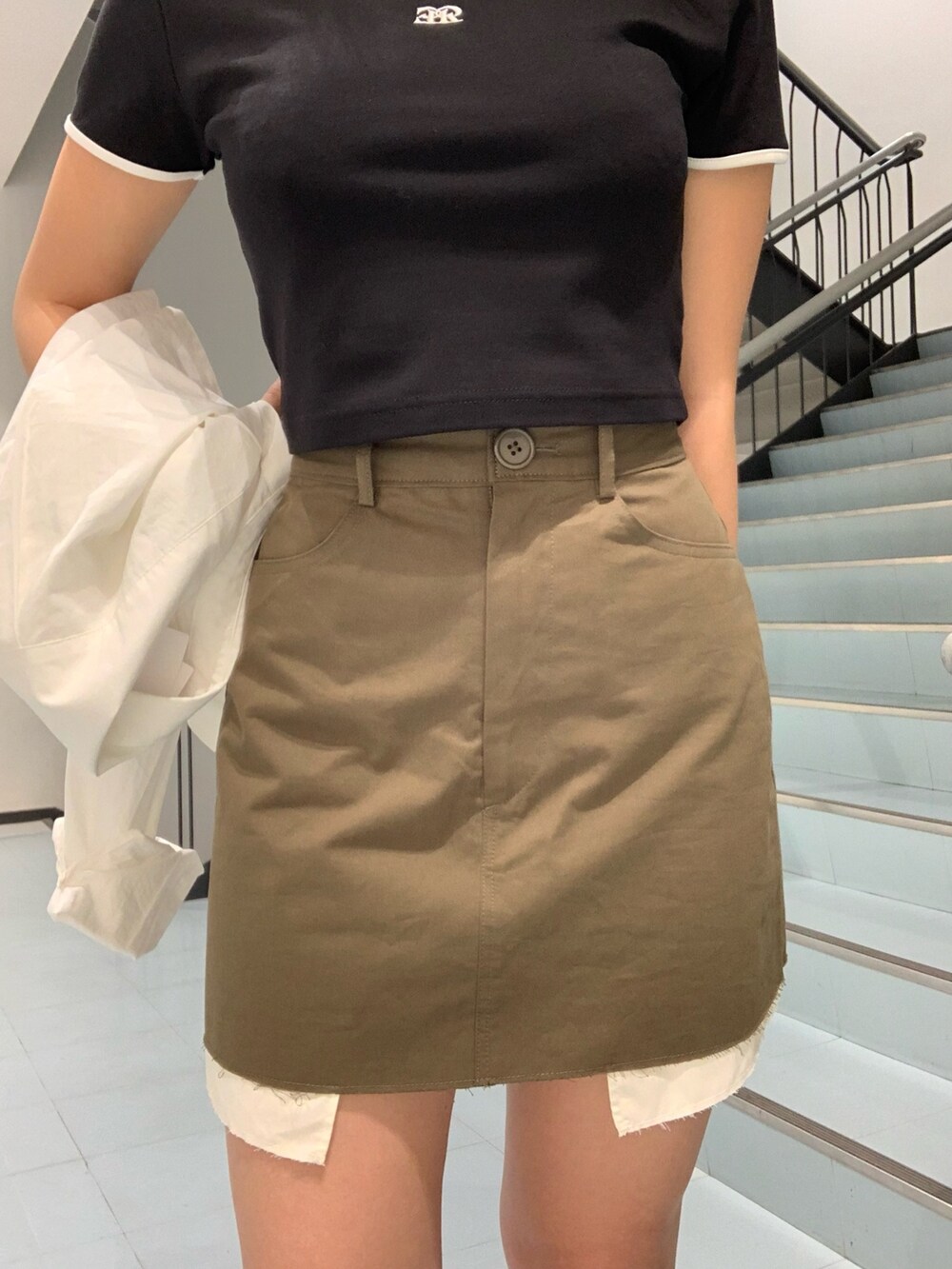 ブラック系のTシャツ/カットソー、ホワイト系のシャツ/ブラウス、グリーン系のスカートを着用したレディースの春コーディネートの5枚目の写真