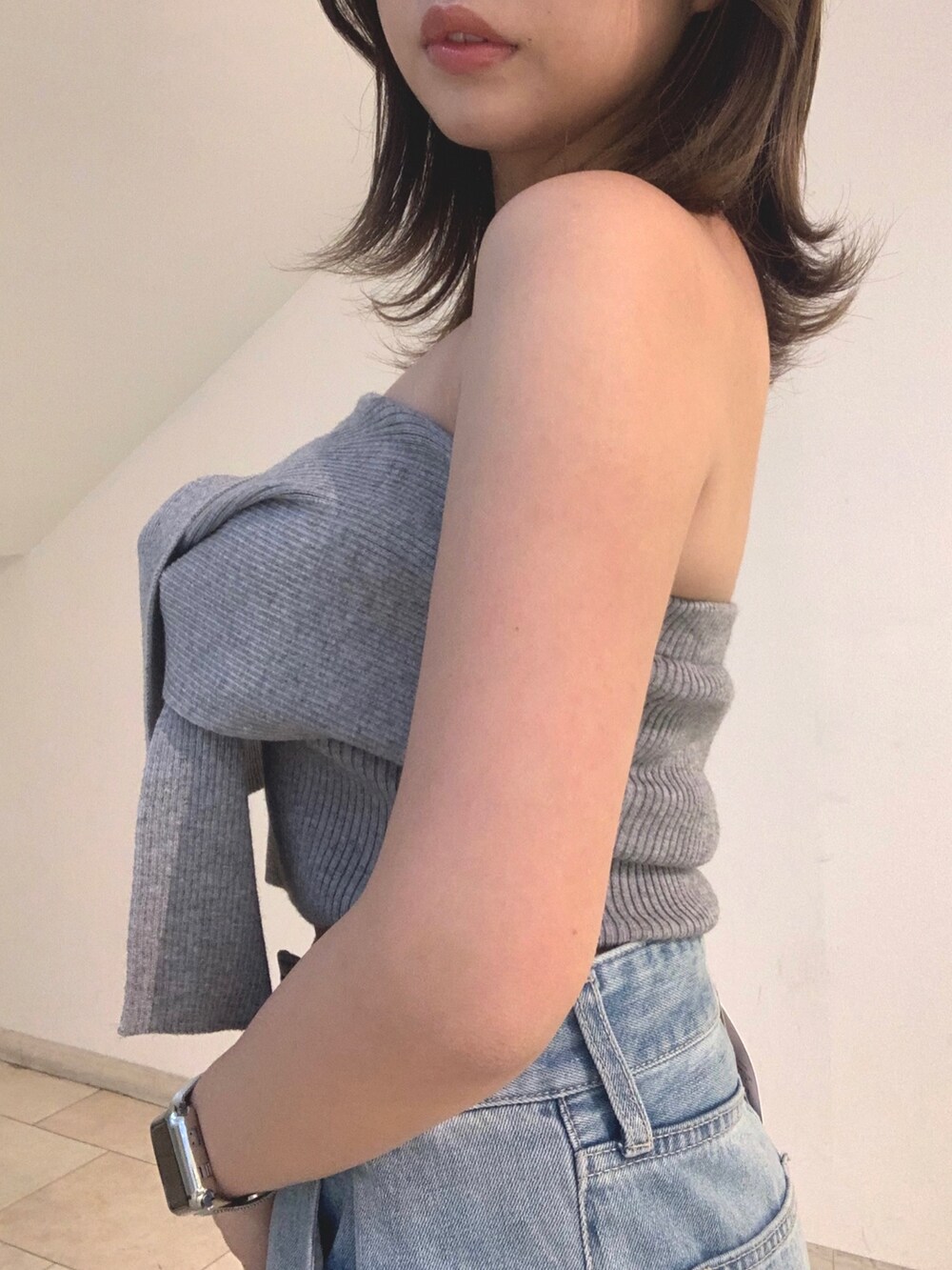 グレー系のチューブトップ、ブルー系のデニムパンツ、シルバー系のショルダーバッグを着用したレディースの春コーディネートの4枚目の写真