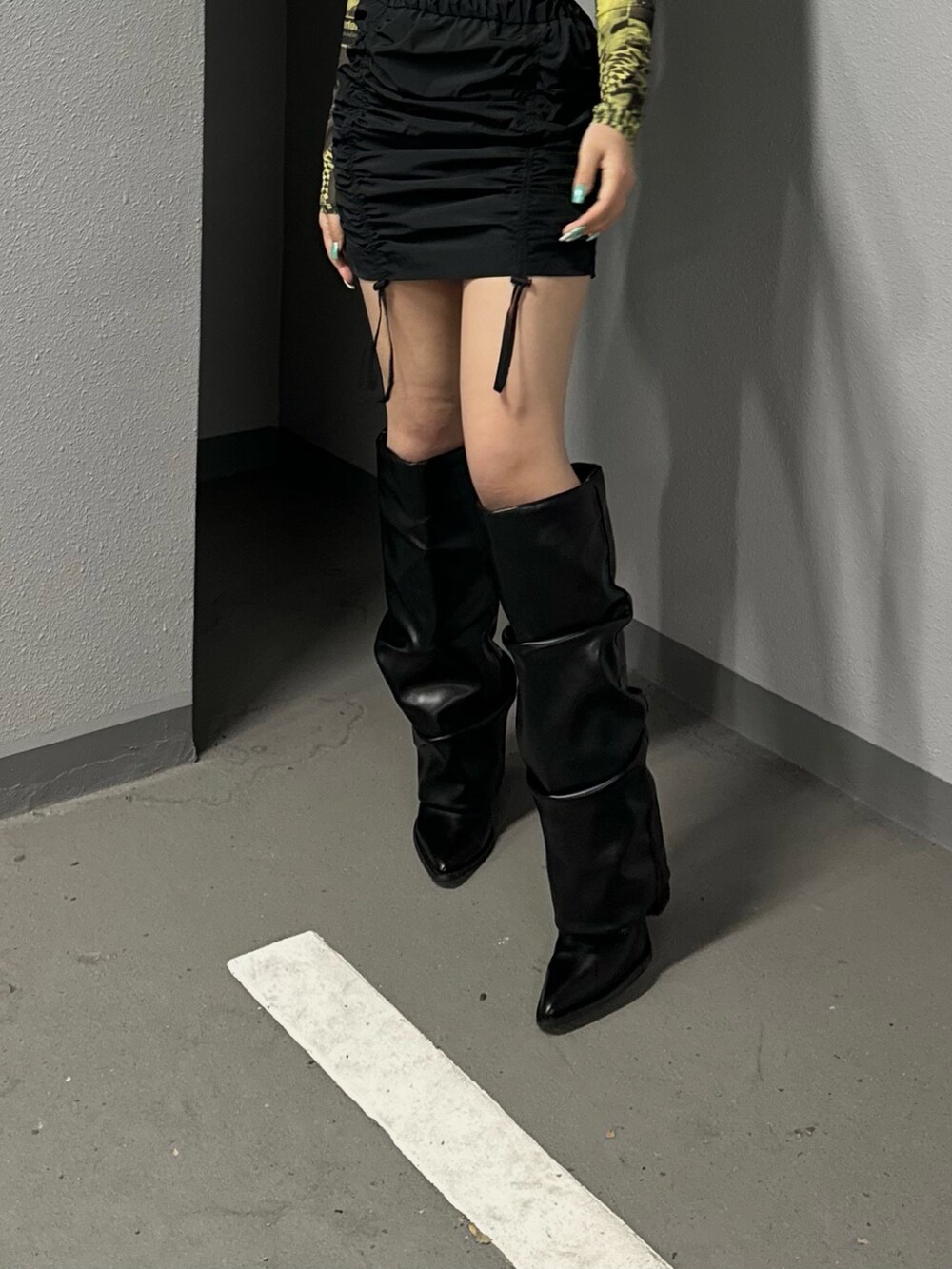 イエロー系のTシャツ/カットソー、ブラック系のスカート、ブラック系のブーツを着用したレディースの冬コーディネートの4枚目の写真