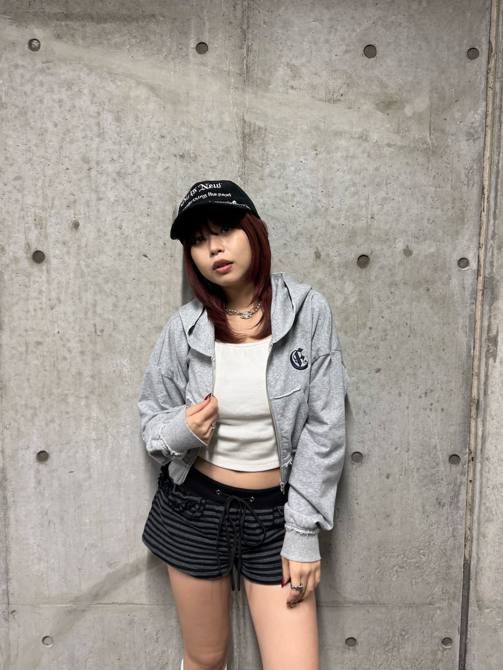 グレー系のパーカー、ブラック系のブーツ、ブラック系のキャップを着用したレディースの秋コーディネートの3枚目の写真