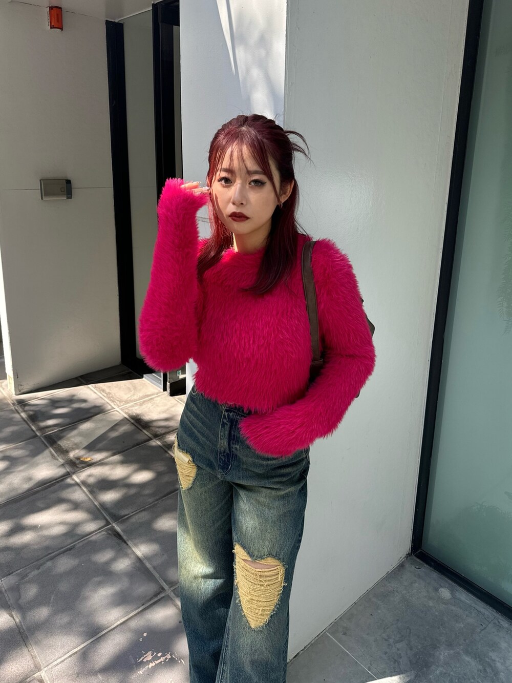 ピンク系のニット/セーター、ブルー系のデニムパンツ、ブラウン系のハンドバッグを着用したレディースの秋コーディネートの3枚目の写真