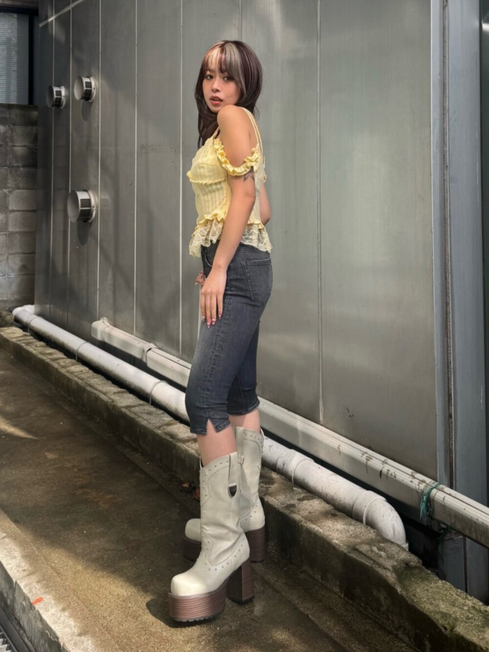 ホワイト系のハンドバッグ、イエロー系のキャミソール、ブラック系のデニムパンツを着用したレディースの春コーディネートの2枚目の写真