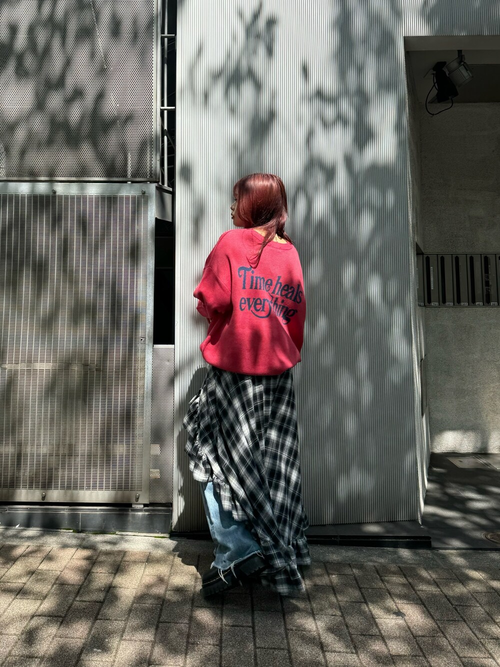 ピンク系のニット/セーター、ブラック系のスカート、ブルー系のデニムパンツを着用したレディースの秋コーディネートの2枚目の写真