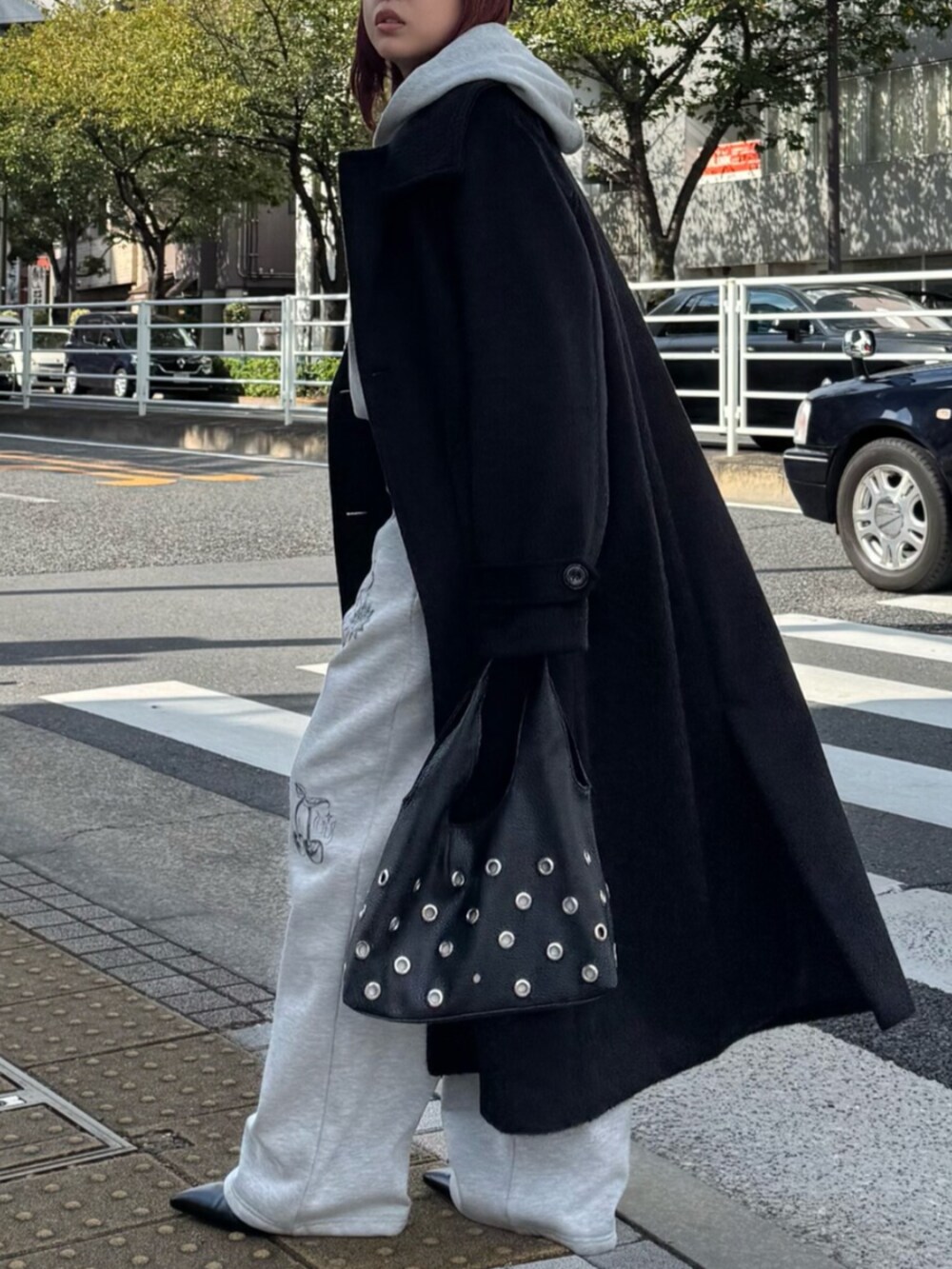 グレー系のスウェットパンツ、グレー系のパーカー、ブラック系のチェスターコートを着用したレディースの秋コーディネートの3枚目の写真