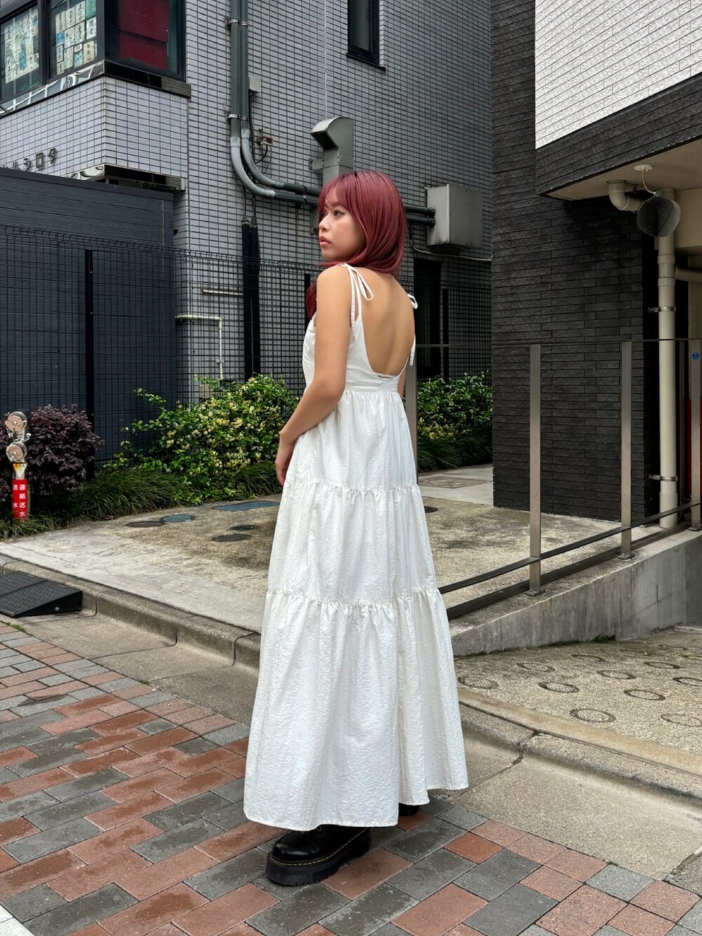 ホワイト系のワンピース、ブラック系のブーツを着用したレディースの夏コーディネートの2枚目の写真