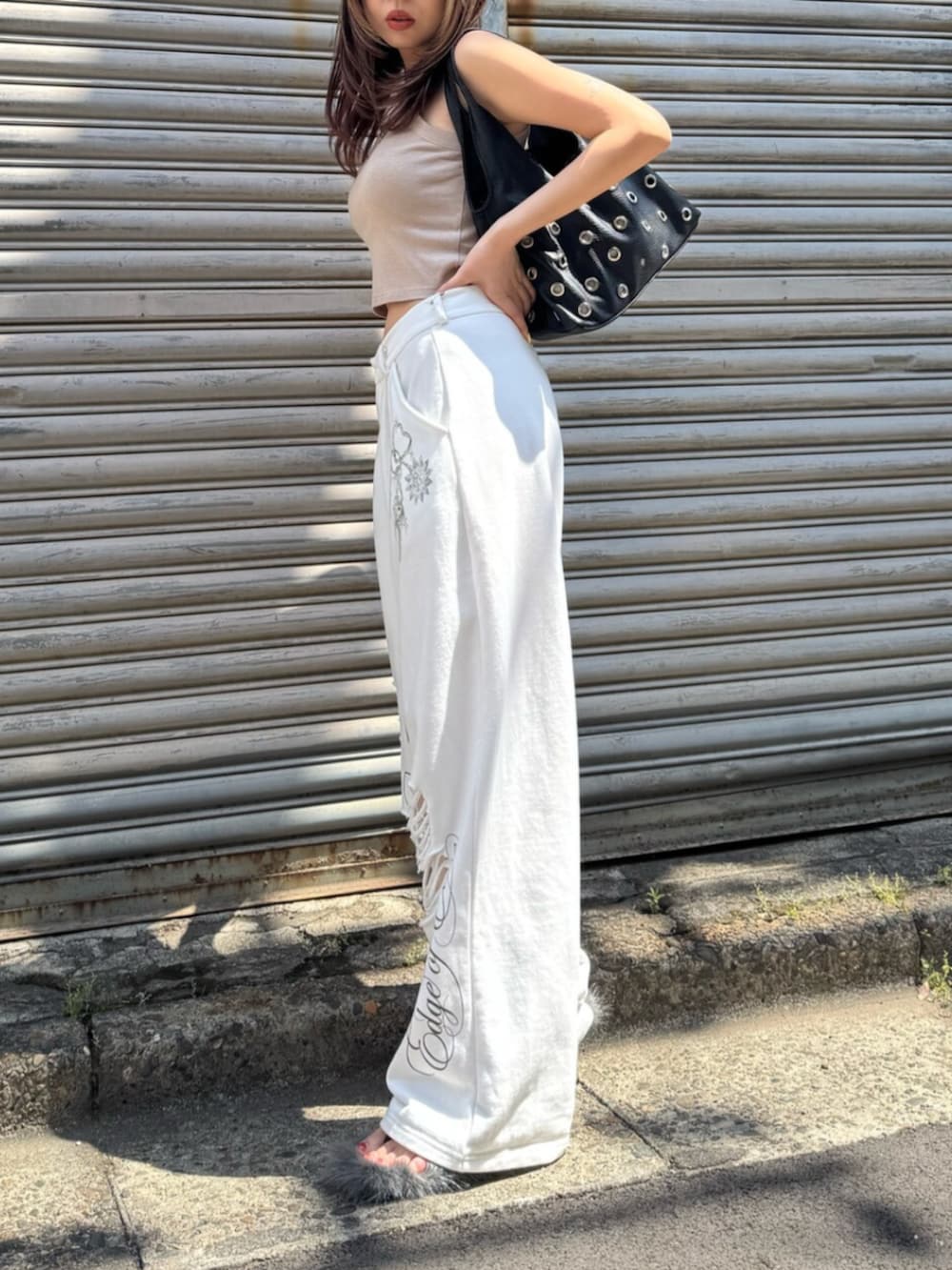 ベージュ系のタンクトップ、ホワイト系のスウェットパンツ、ブラック系のサンダルを着用したレディースの夏コーディネートの2枚目の写真