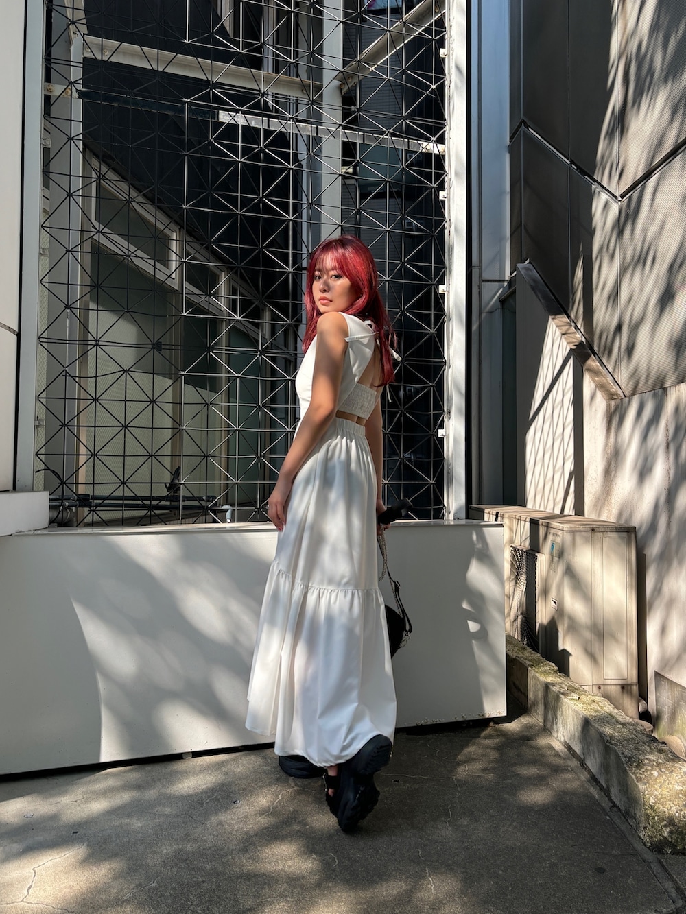 ホワイト系のワンピース、ブラック系のショルダーバッグ、ブラック系のサンダルを着用したレディースの夏コーディネートの2枚目の写真