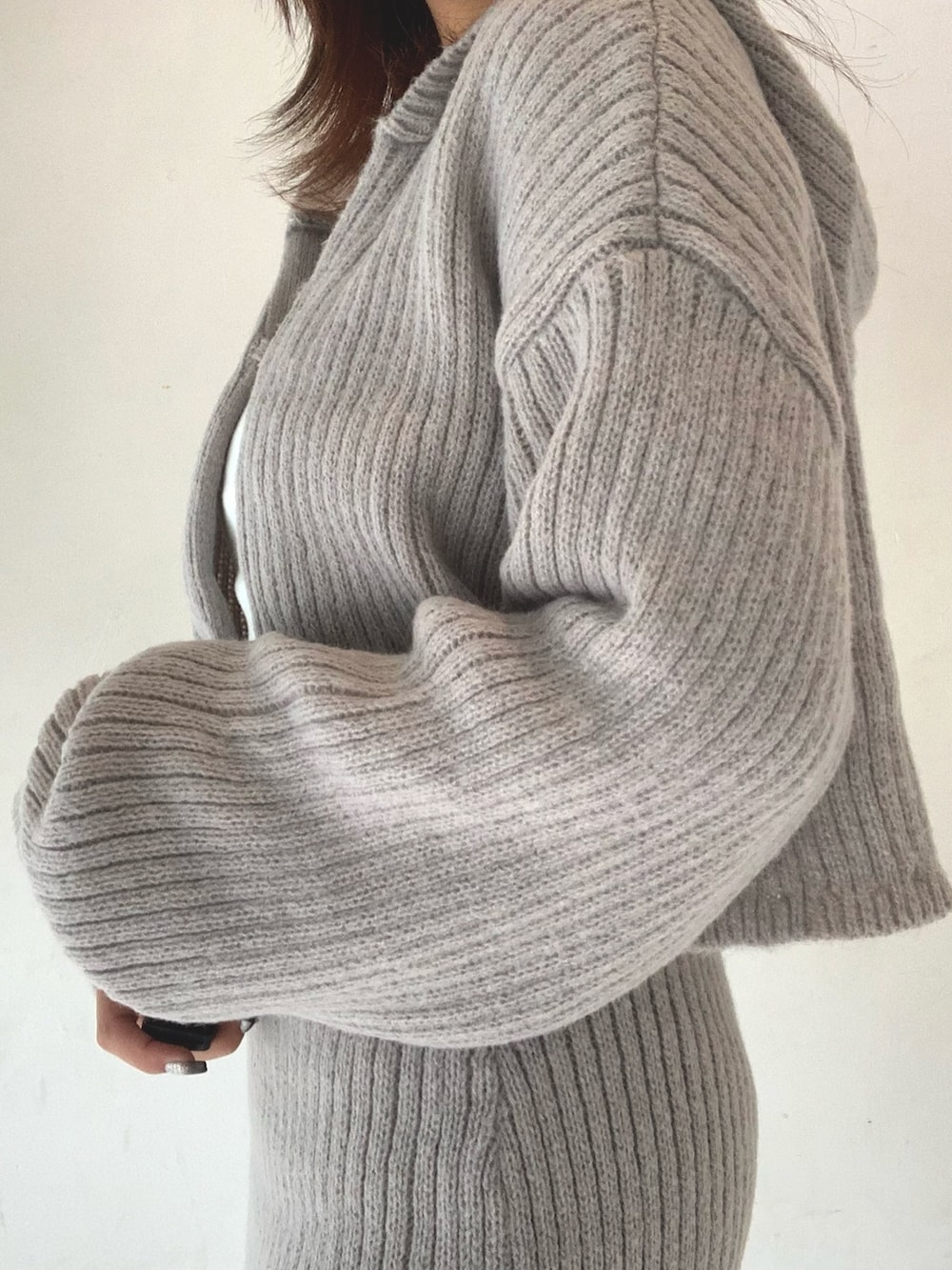 グレー系のスカート、ホワイト系のTシャツ/カットソー、グレー系のカーディガン/ボレロを着用したレディースの秋コーディネートの4枚目の写真