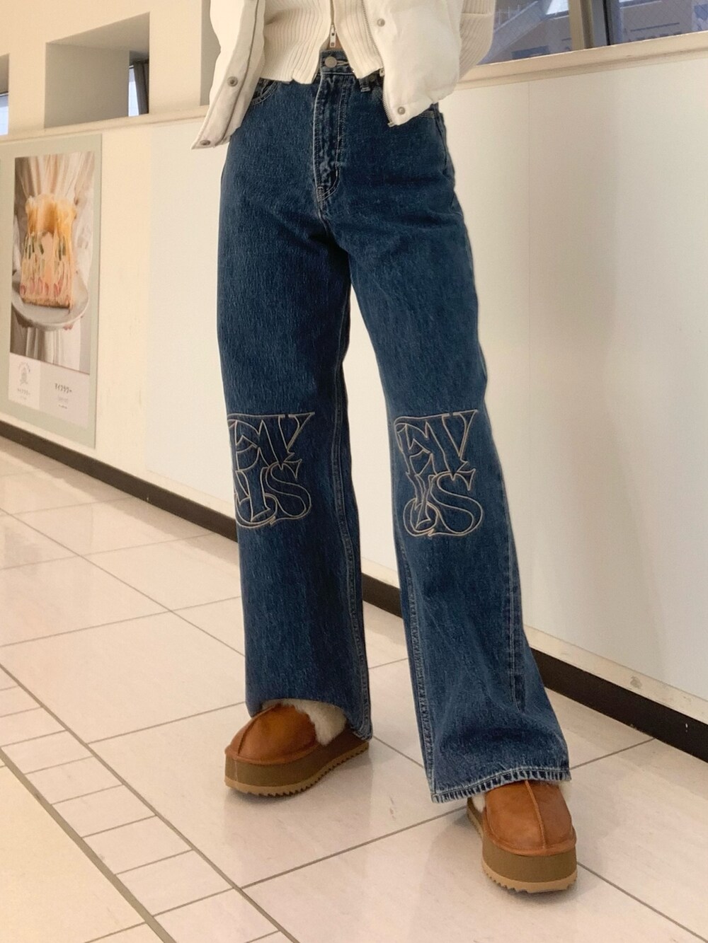 ホワイト系のダウンベスト、ホワイト系のニット/セーター、ブルー系のデニムパンツを着用したレディースの秋コーディネートの5枚目の写真