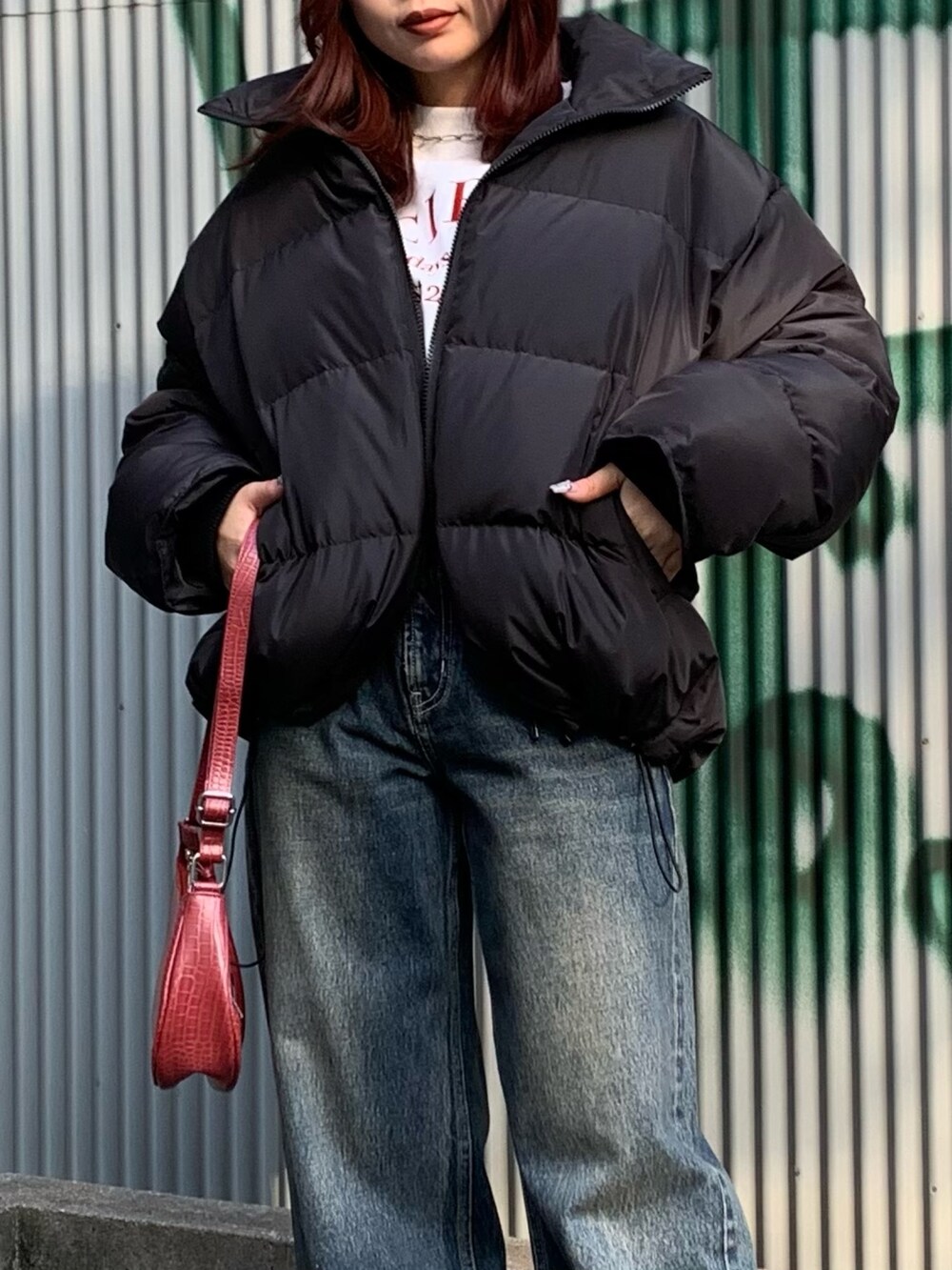 ブルー系のデニムパンツ、レッド系のショルダーバッグ、ブラック系のダウンジャケット/コートを着用したレディースの冬コーディネートの4枚目の写真