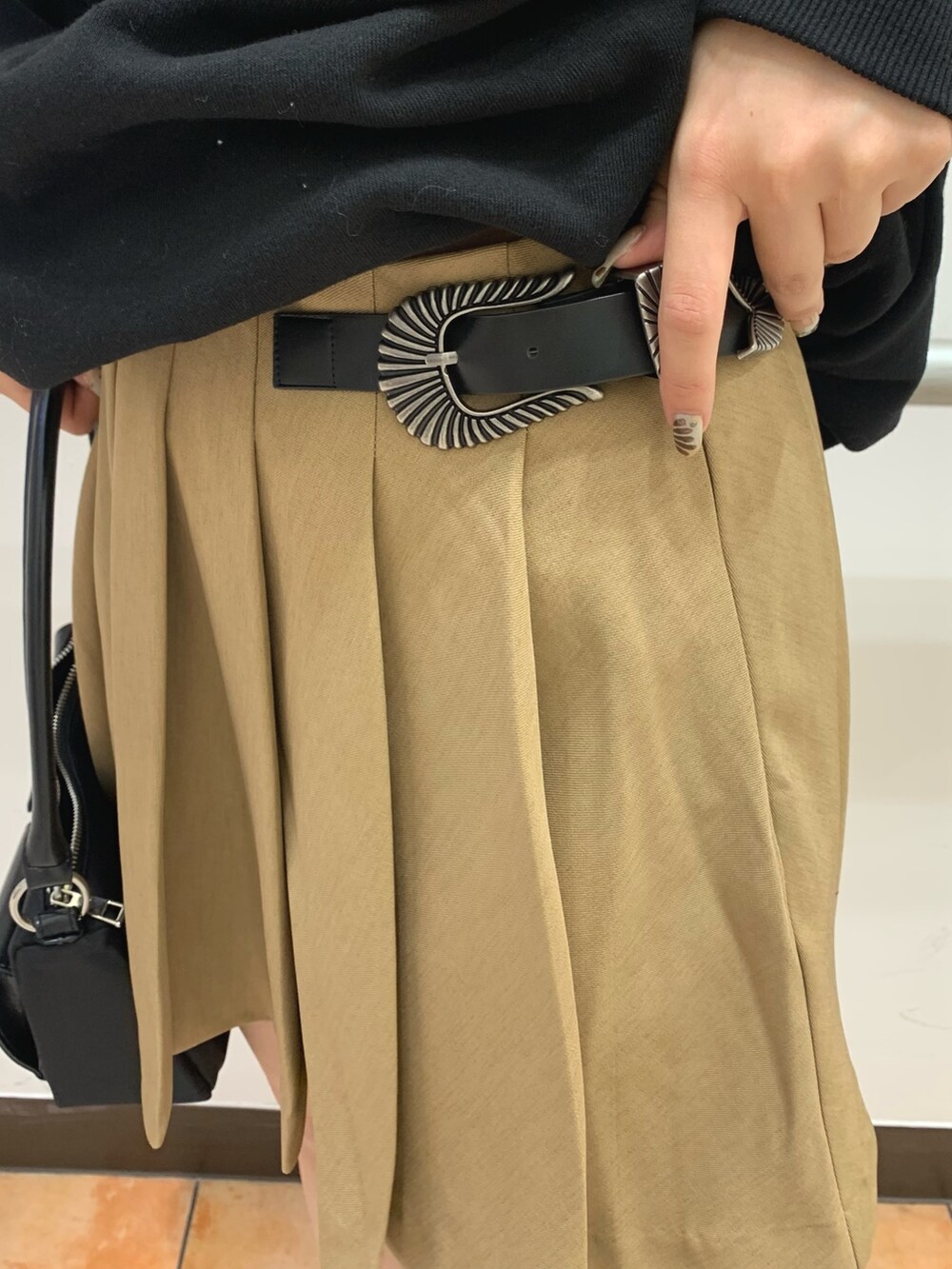 ブラック系のスウェット、ベージュ系のスカート、ブラック系のハンドバッグを着用したレディースの秋コーディネートの5枚目の写真