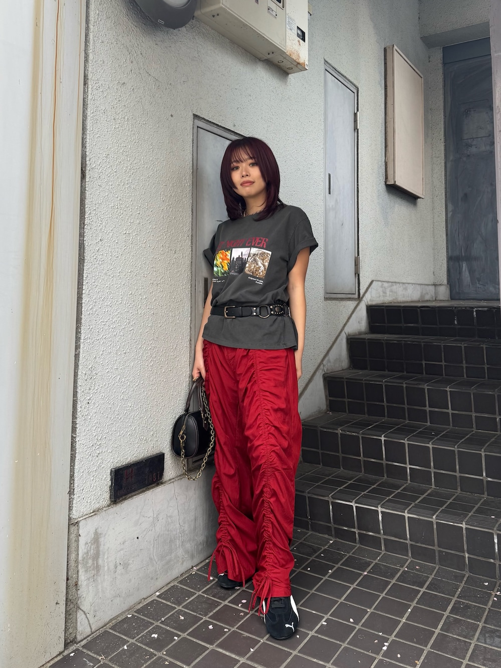 ブラック系のTシャツ/カットソー、ブラック系のショルダーバッグ、レッド系のその他パンツを着用したレディースの春コーディネートの2枚目の写真