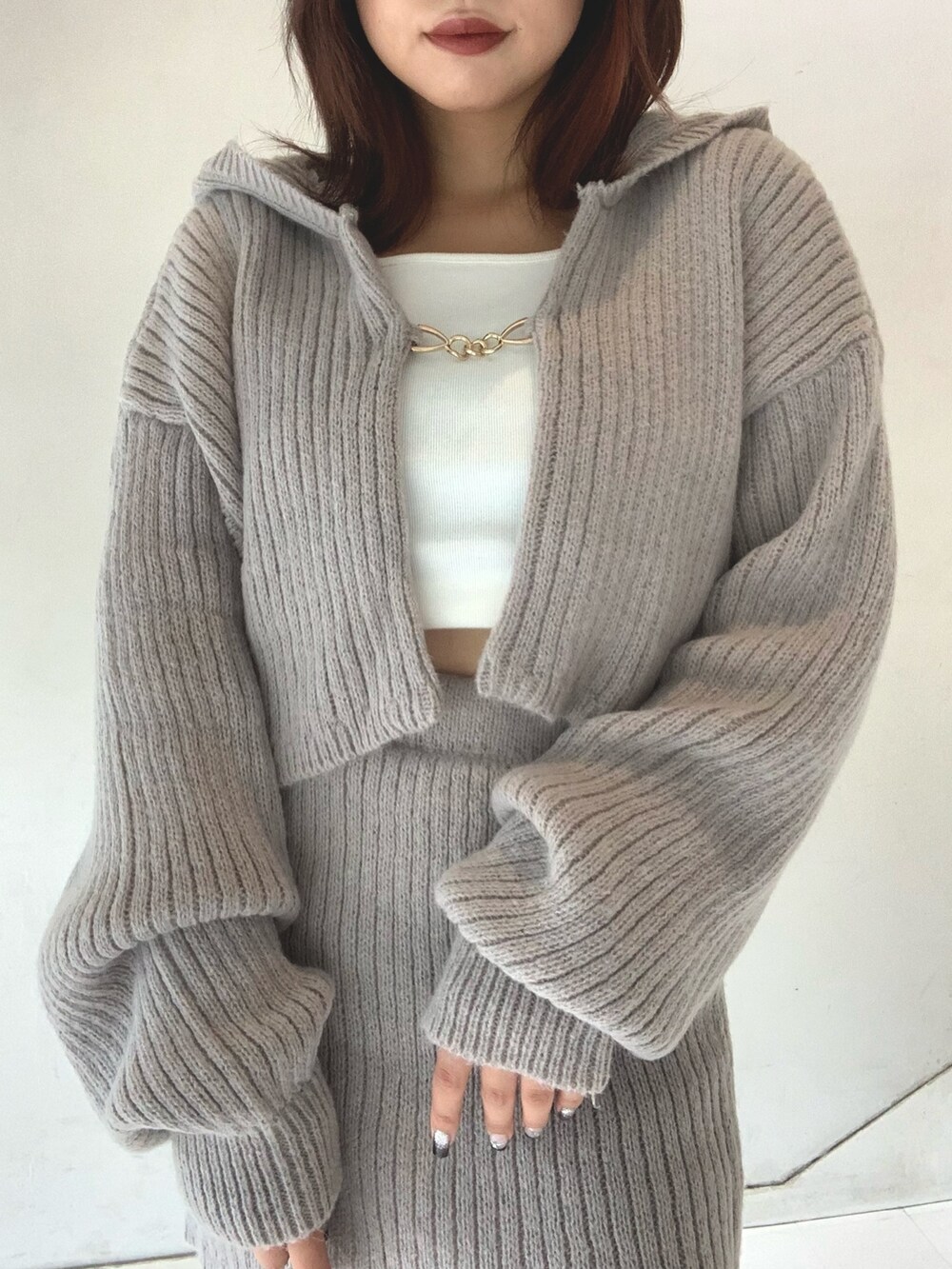 グレー系のスカート、ホワイト系のTシャツ/カットソー、グレー系のカーディガン/ボレロを着用したレディースの秋コーディネートの3枚目の写真