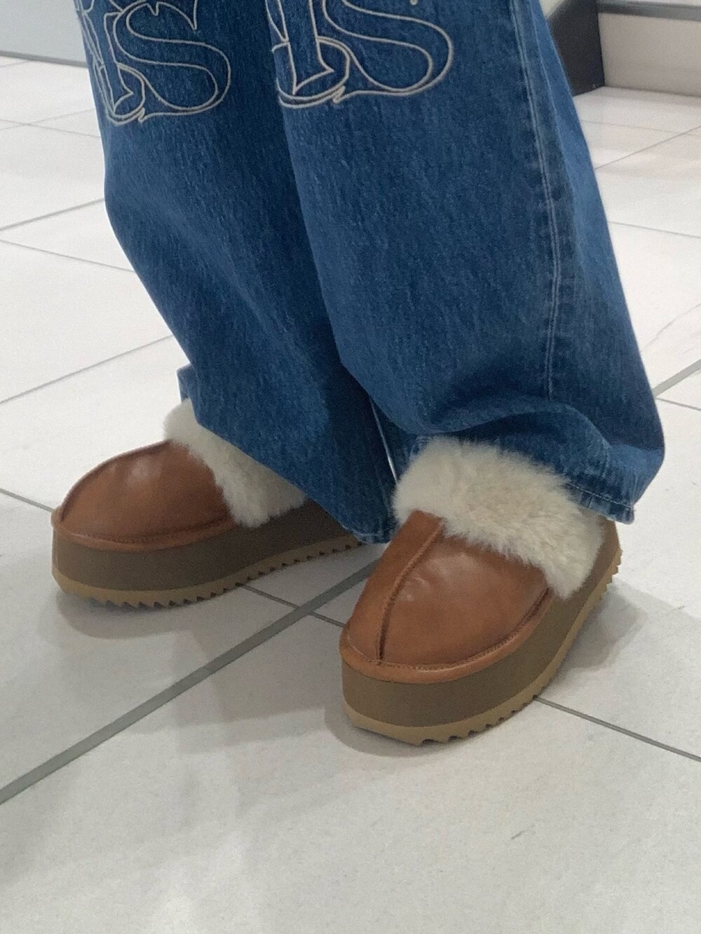 ホワイト系のダウンベスト、ホワイト系のニット/セーター、ブルー系のデニムパンツを着用したレディースの秋コーディネートの7枚目の写真