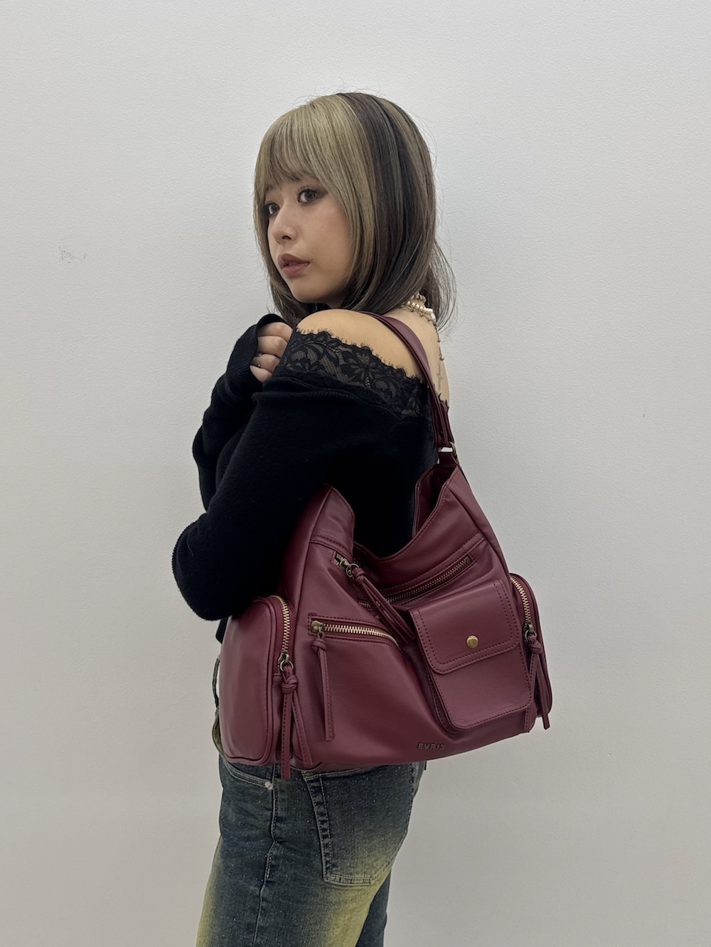 ブラック系のニット/セーター、ブルー系のデニムパンツ、レッド系のハンドバッグを着用したレディースの秋コーディネートの5枚目の写真