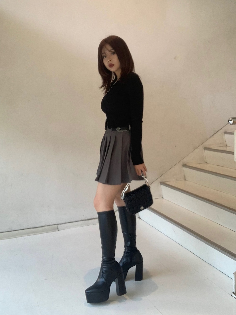 ブラック系のニット/セーター、グレー系のスカート、ブラック系のブーツを着用したレディースの秋コーディネートの2枚目の写真