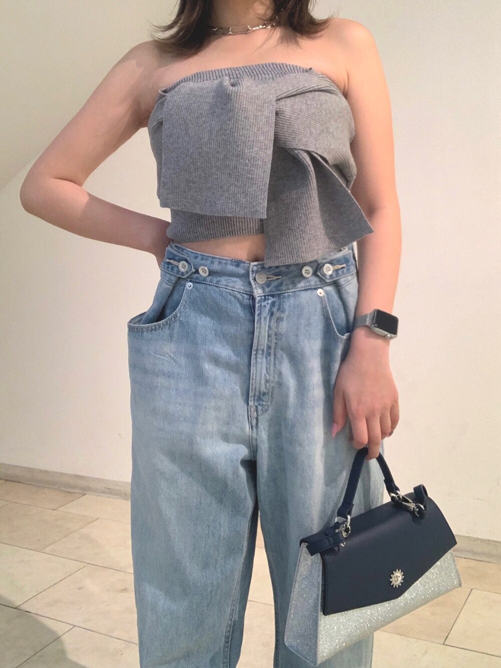 グレー系のチューブトップ、ブルー系のデニムパンツ、シルバー系のショルダーバッグを着用したレディースの春コーディネートの5枚目の写真