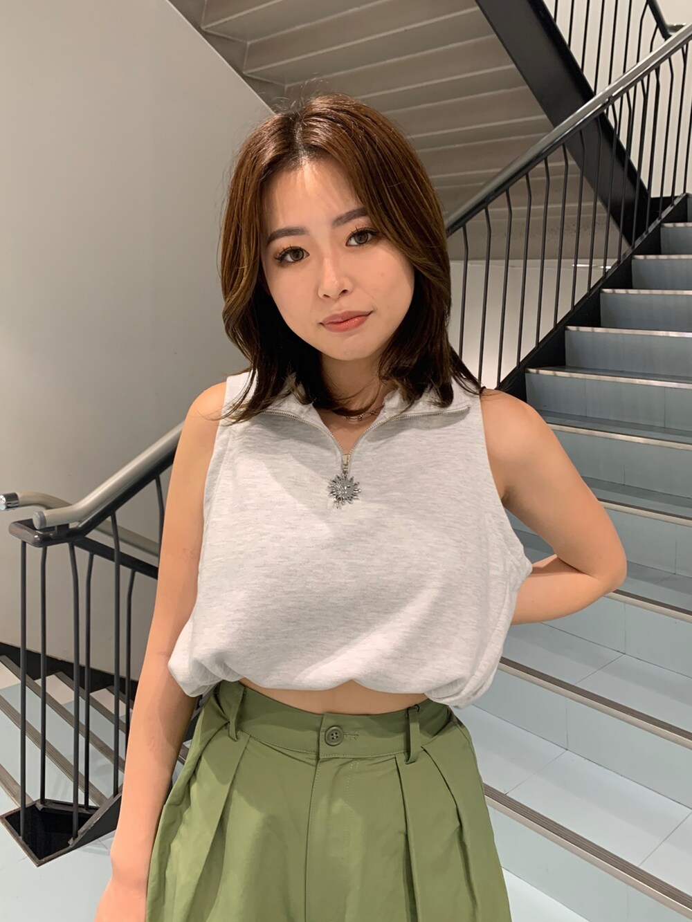 グレー系のタンクトップ、グリーン系のカーゴパンツ、ホワイト系のショルダーバッグを着用したレディースの春コーディネートの5枚目の写真