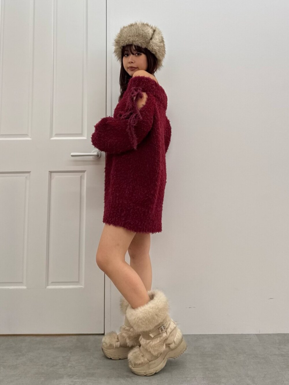 レッド系のワンピース、ベージュ系のキャップを着用したレディースの冬コーディネートの2枚目の写真
