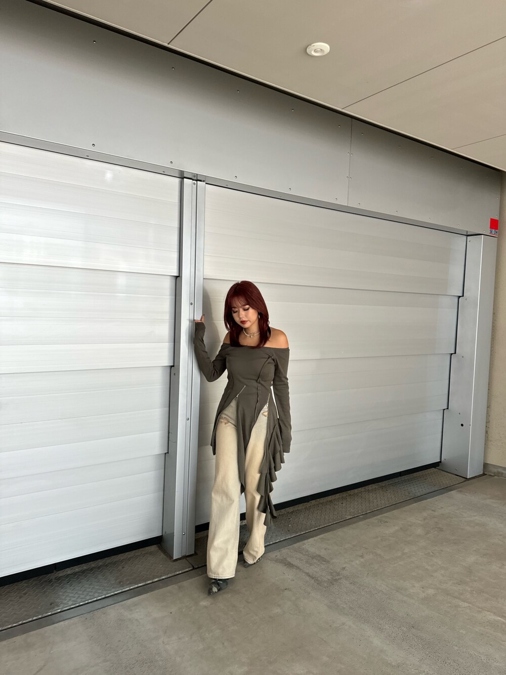 グリーン系のワンピース、ベージュ系のデニムパンツ、グリーン系のサンダルを着用したレディースの冬コーディネートの4枚目の写真