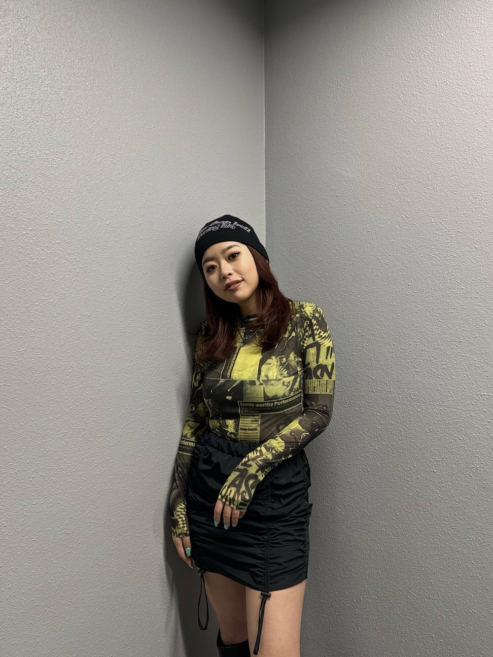 イエロー系のTシャツ/カットソー、ブラック系のスカート、ブラック系のブーツを着用したレディースの冬コーディネートの3枚目の写真