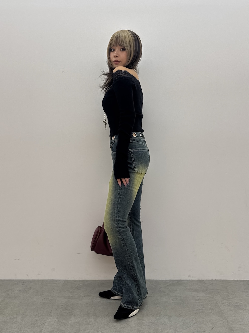 ブラック系のニット/セーター、ブルー系のデニムパンツ、レッド系のハンドバッグを着用したレディースの秋コーディネートの2枚目の写真