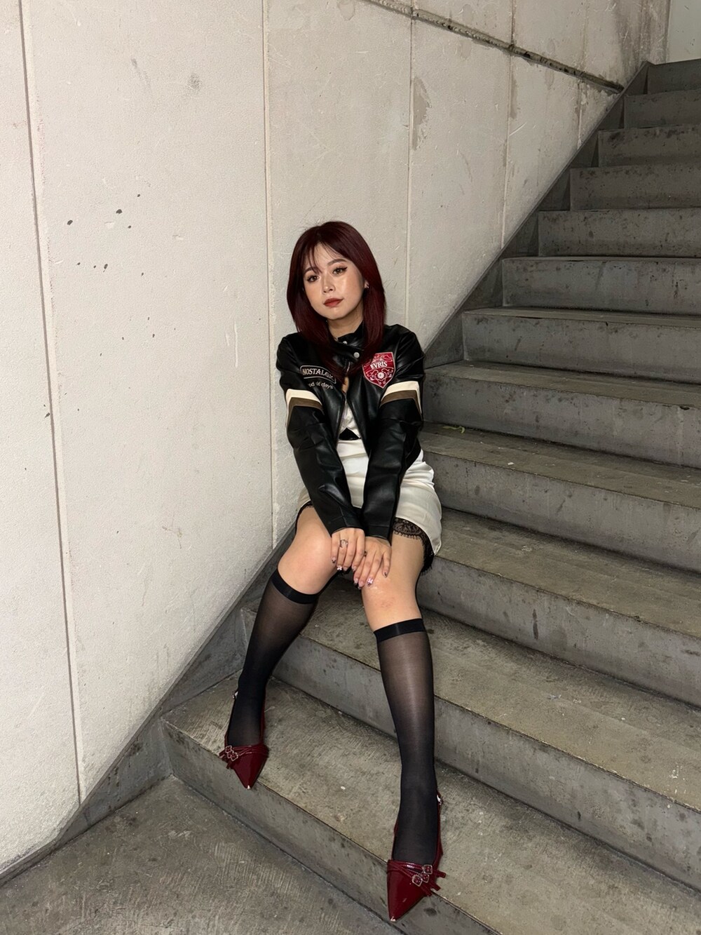 ブラック系のライダースジャケット、ホワイト系のワンピースを着用したレディースの秋コーディネートの3枚目の写真