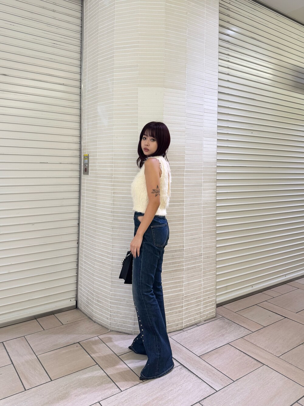 ホワイト系のタンクトップ、ブルー系のデニムパンツ、ブラック系のショルダーバッグを着用したレディースの夏コーディネートの2枚目の写真