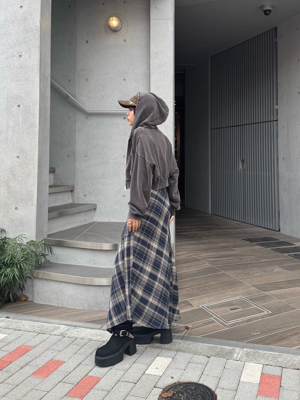 ブルー系のスカート、ブラック系のニット/セーター、ブラック系のブーツを着用したレディースの秋コーディネートの2枚目の写真