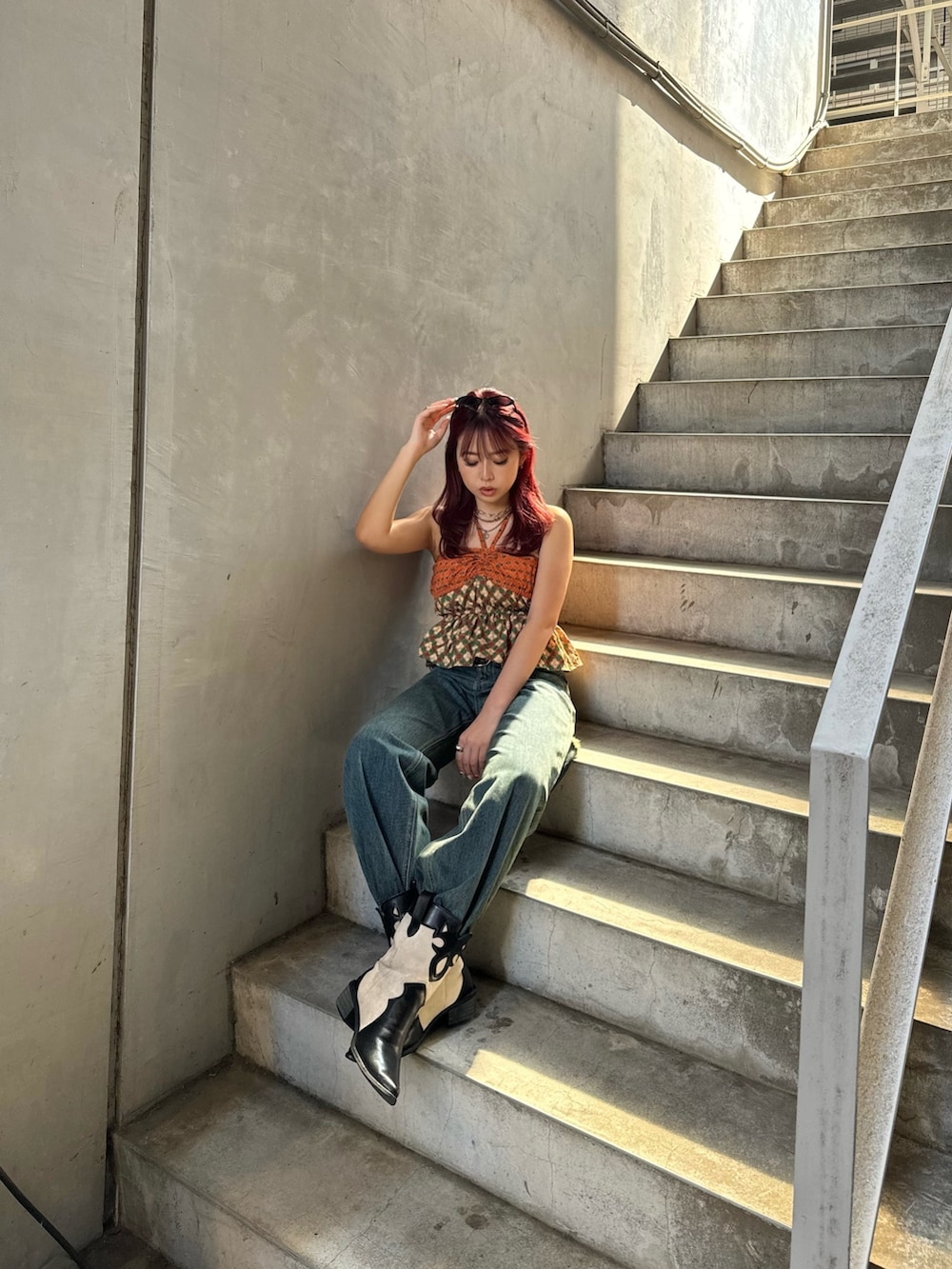 オレンジ系のキャミソール、ブルー系のデニムパンツを着用したレディースの夏コーディネートの2枚目の写真