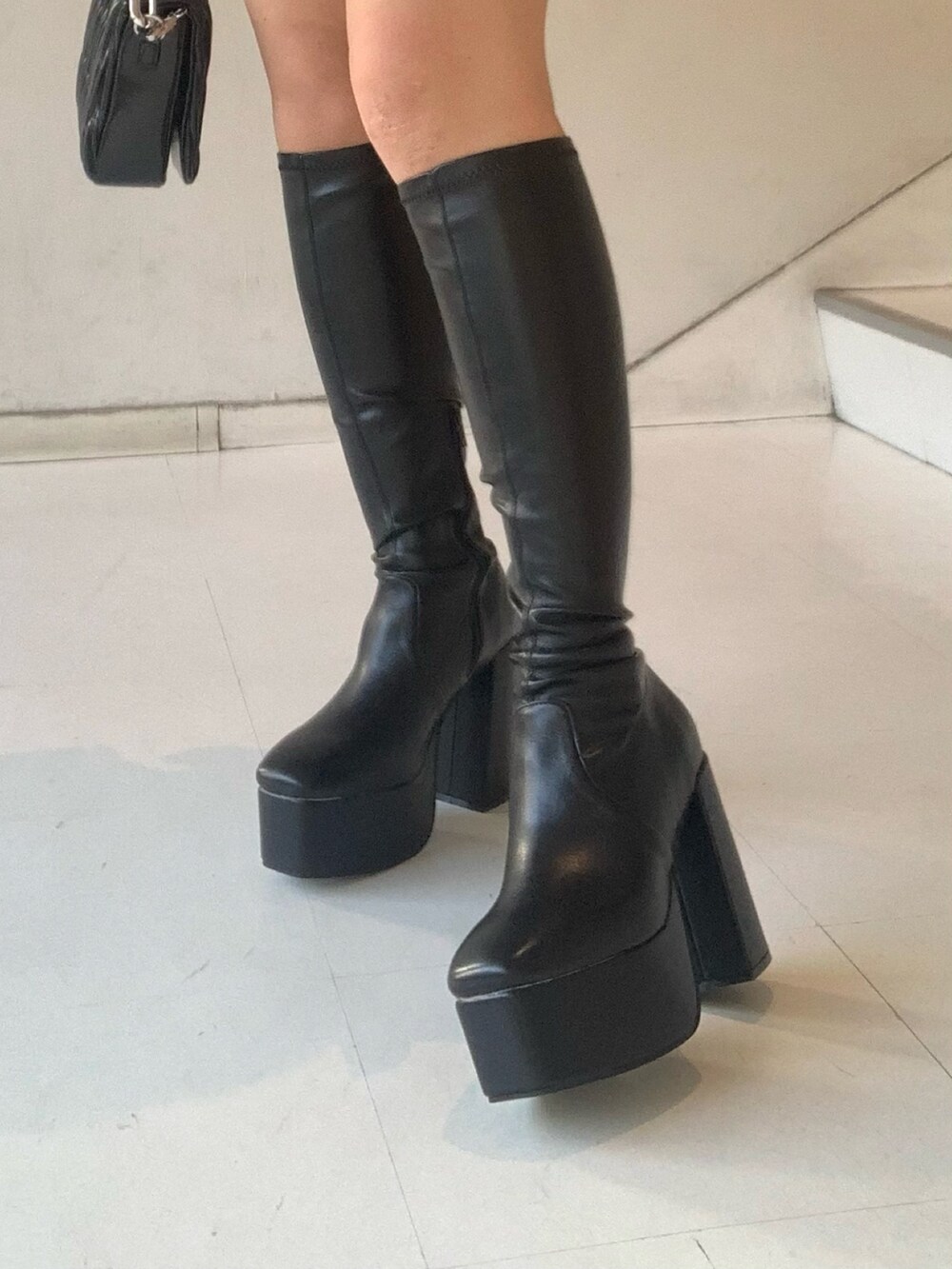 ブラック系のニット/セーター、グレー系のスカート、ブラック系のブーツを着用したレディースの秋コーディネートの7枚目の写真