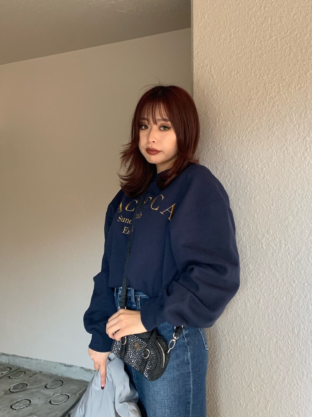 ブラック系のハンドバッグ、ブルー系のスウェット、グレー系のダウンジャケット/コートを着用したレディースの冬コーディネートの4枚目の写真