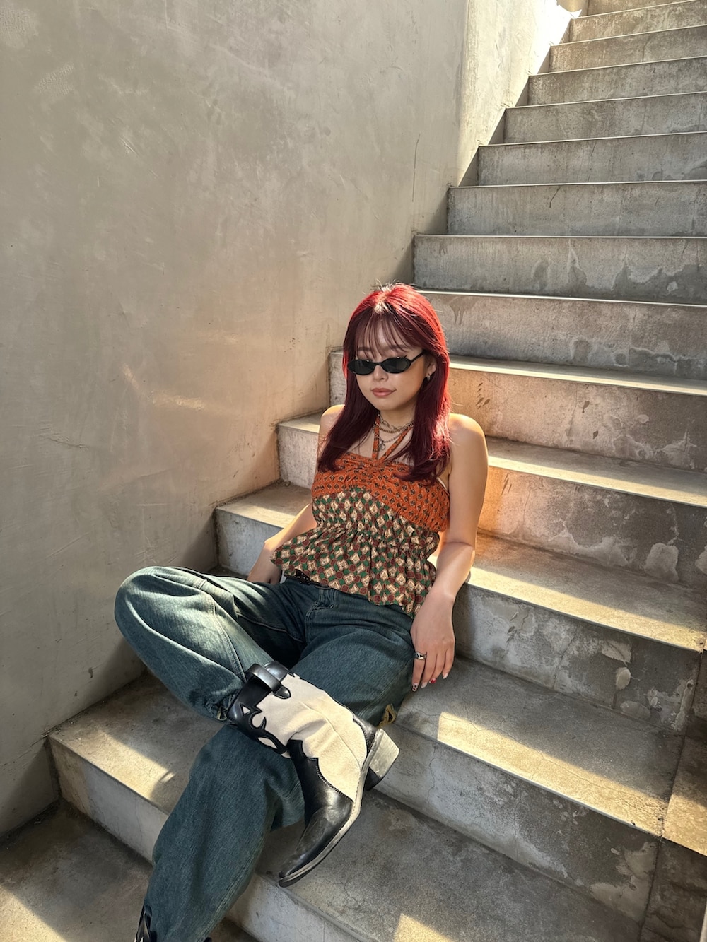 オレンジ系のキャミソール、ブルー系のデニムパンツを着用したレディースの夏コーディネートの3枚目の写真