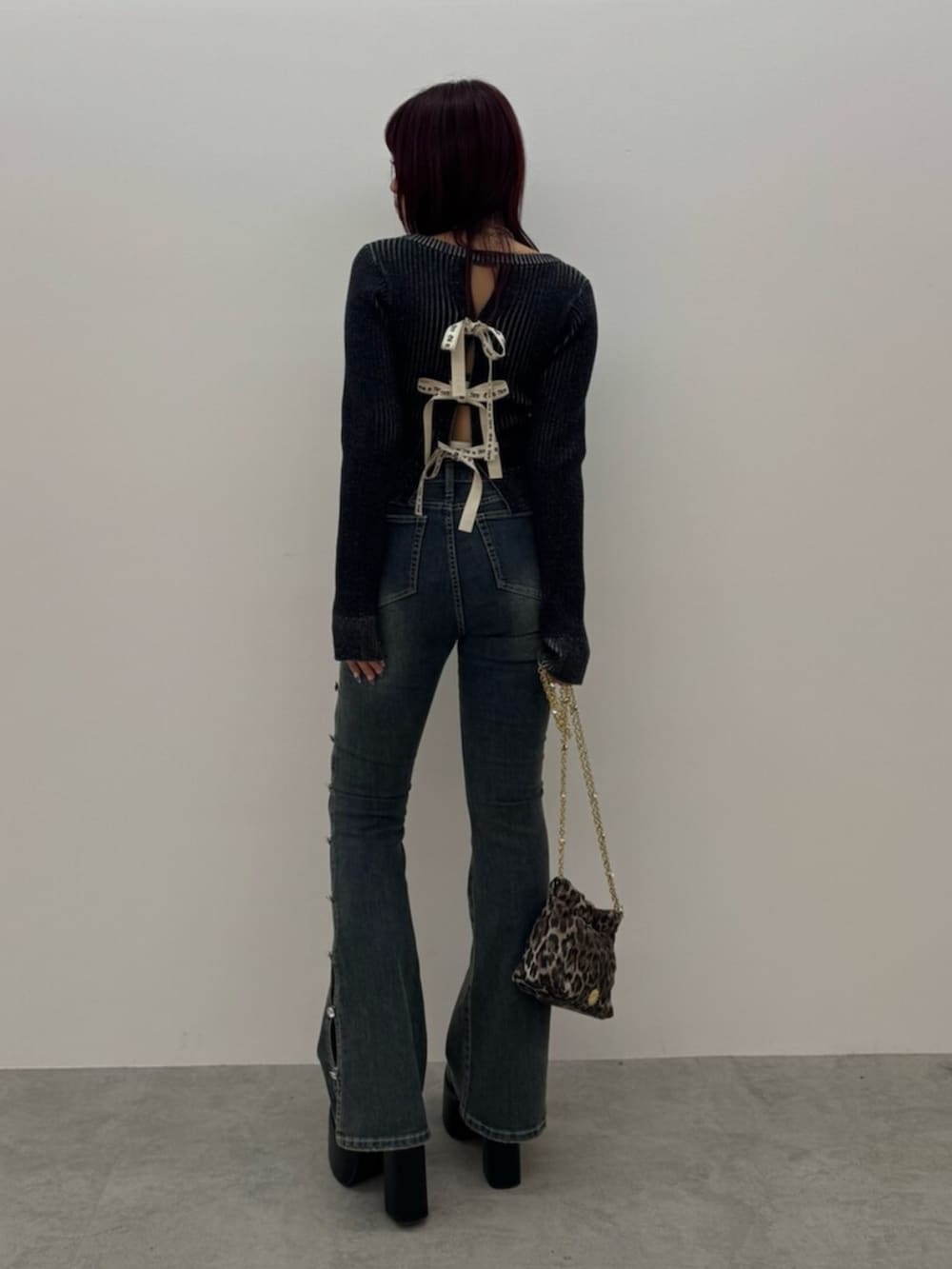 ブラック系のブーツ、ブラック系のニット/セーター、ブルー系のデニムパンツを着用したレディースの冬コーディネートの3枚目の写真