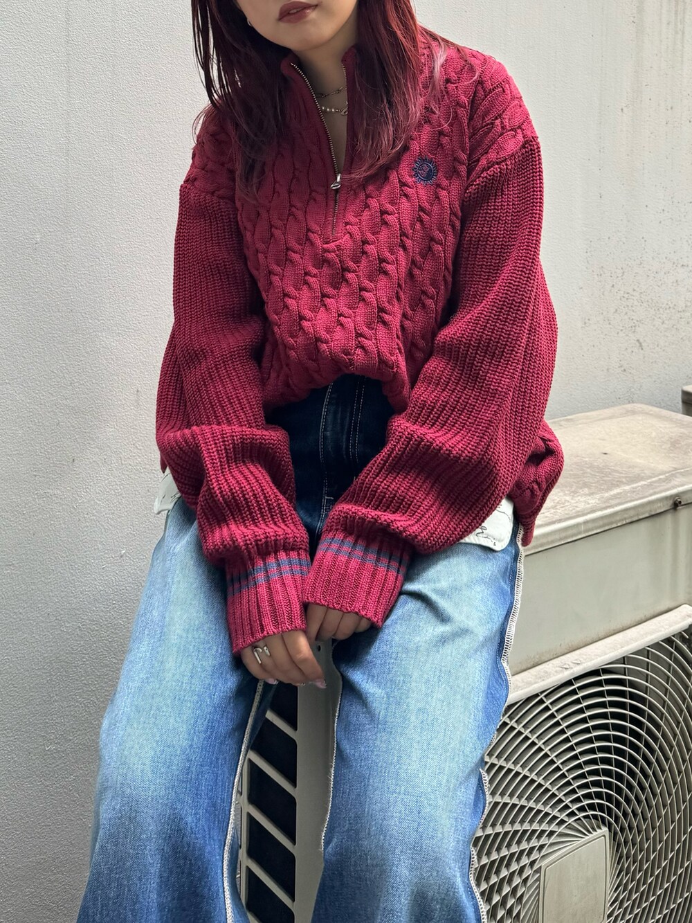 レッド系のニット/セーター、ブルー系のデニムパンツを着用したレディースの夏コーディネートの3枚目の写真