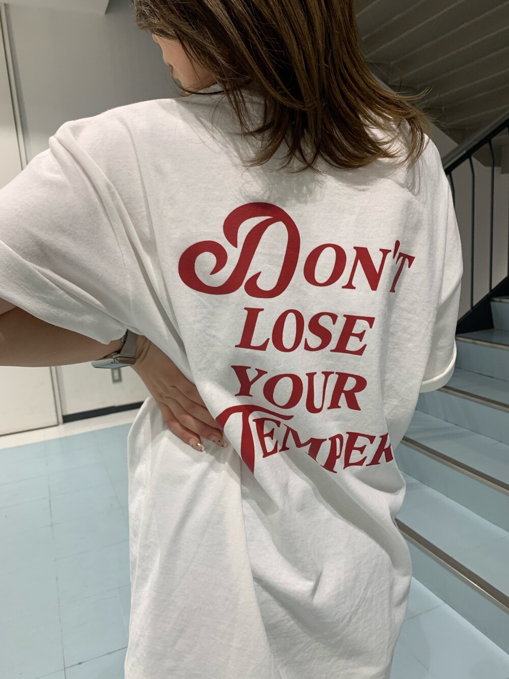 ホワイト系のTシャツ/カットソー、ホワイト系のハンドバッグ、ブラック系のブーツを着用したレディースの春コーディネートの5枚目の写真