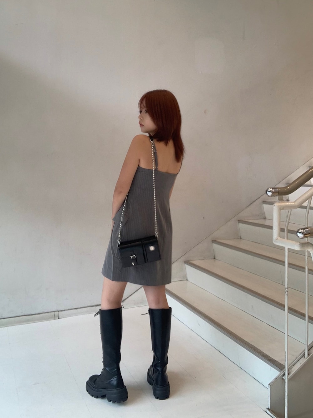 グレー系のワンピース、ブラック系のショルダーバッグ、ブラック系のブーツを着用したレディースの夏コーディネートの3枚目の写真