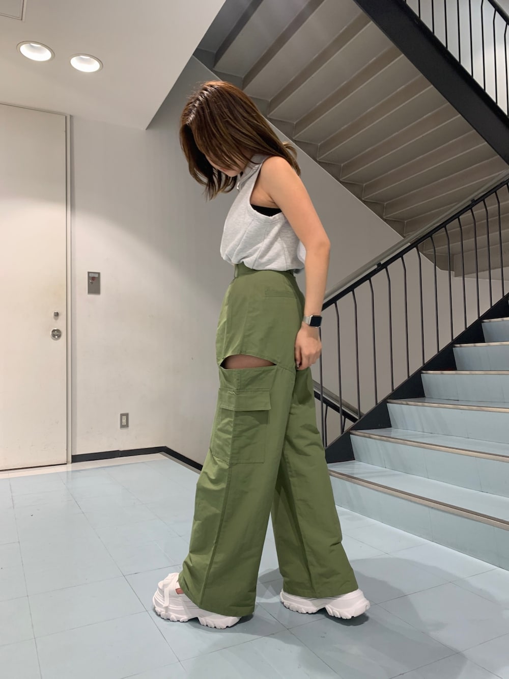 グレー系のタンクトップ、グリーン系のカーゴパンツ、ホワイト系のショルダーバッグを着用したレディースの春コーディネートの2枚目の写真