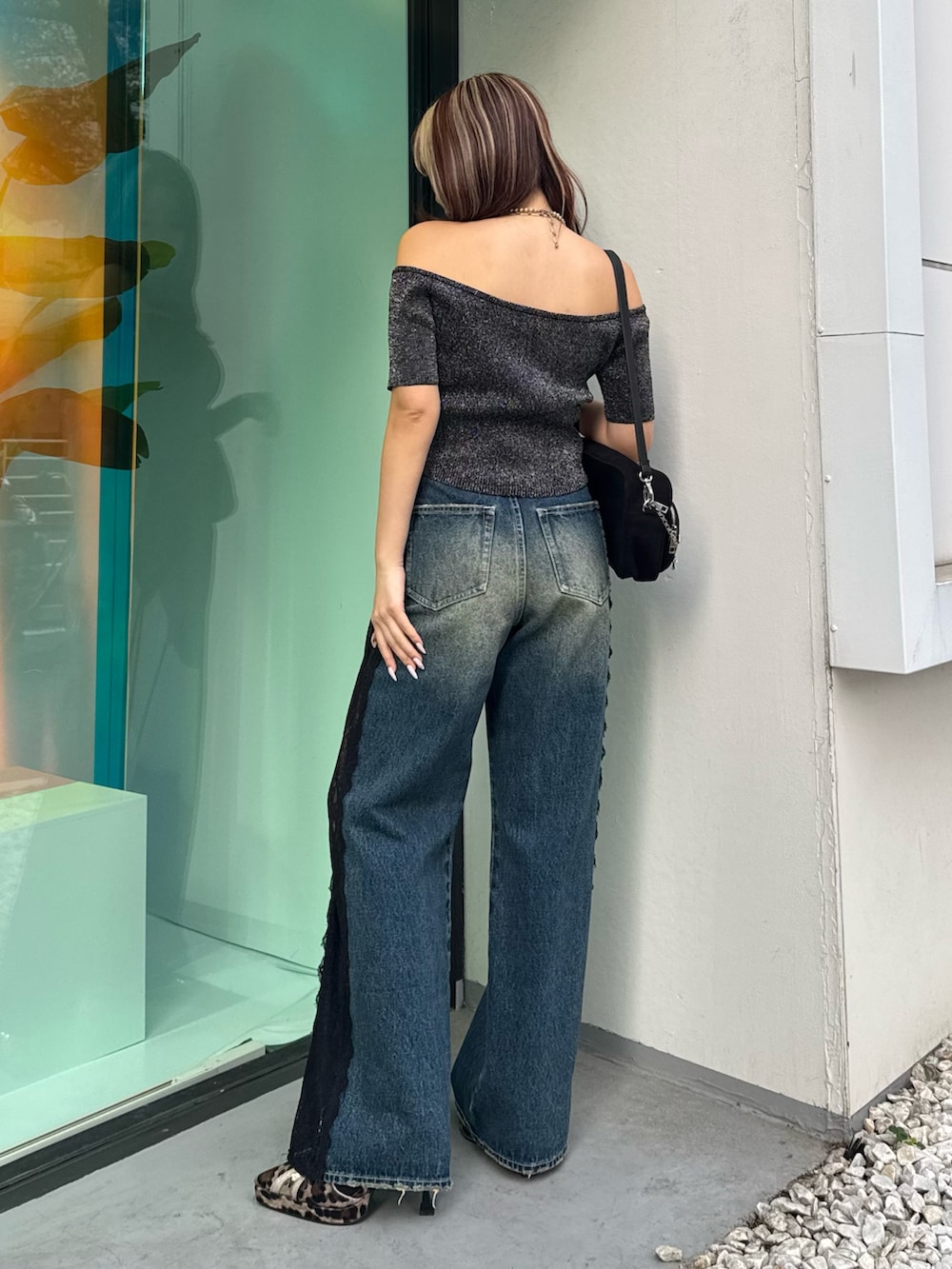 ブラック系のニット/セーター、ブルー系のデニムパンツ、ブラック系のハンドバッグを着用したレディースの春コーディネートの3枚目の写真