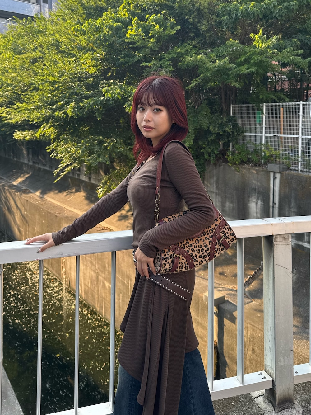 ブルー系のデニムパンツ、ベージュ系のハンドバッグを着用したレディースの秋コーディネートの4枚目の写真